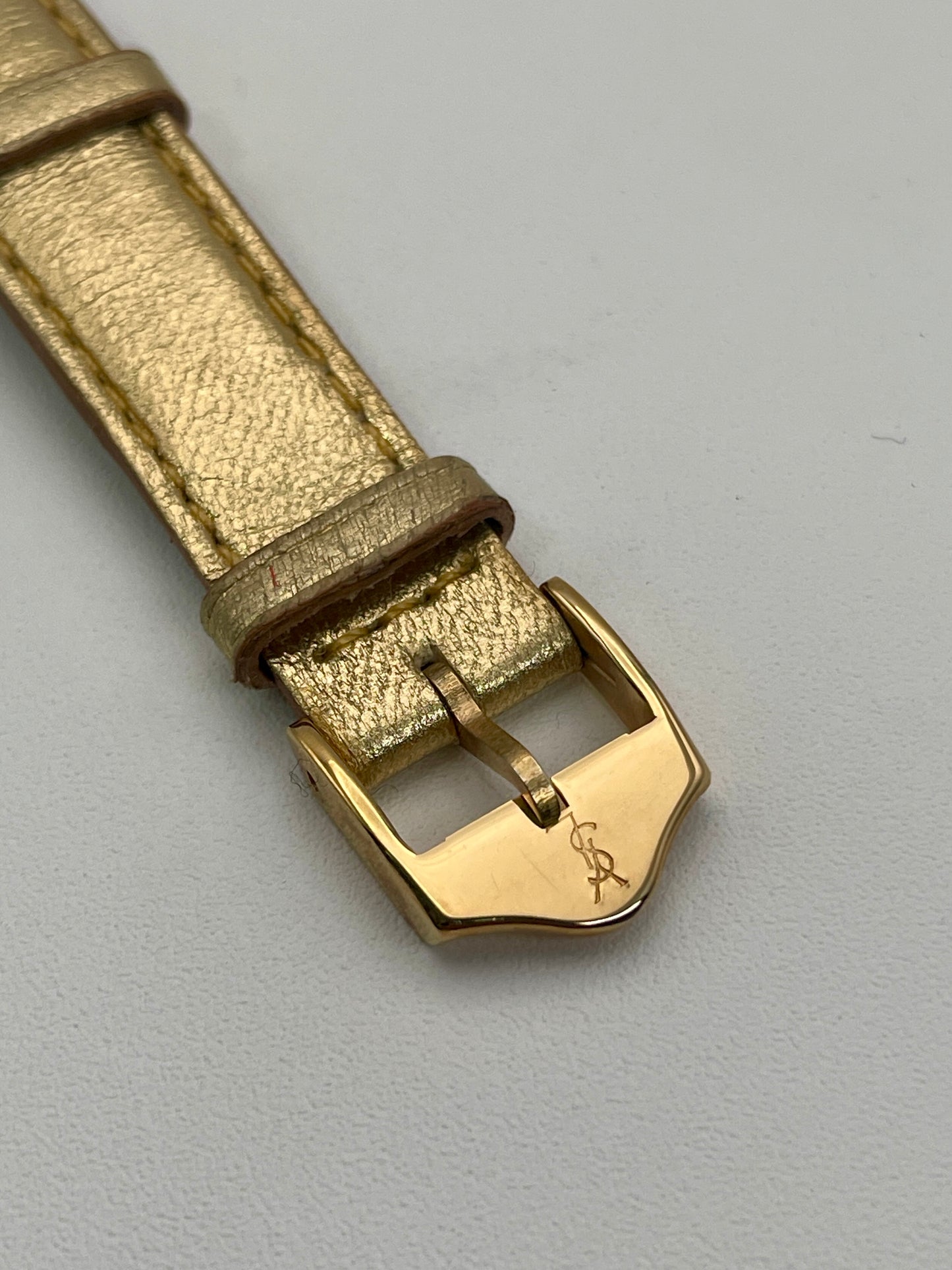 Close-up of the gold YSL-signed buckle and matching gold leather strap.