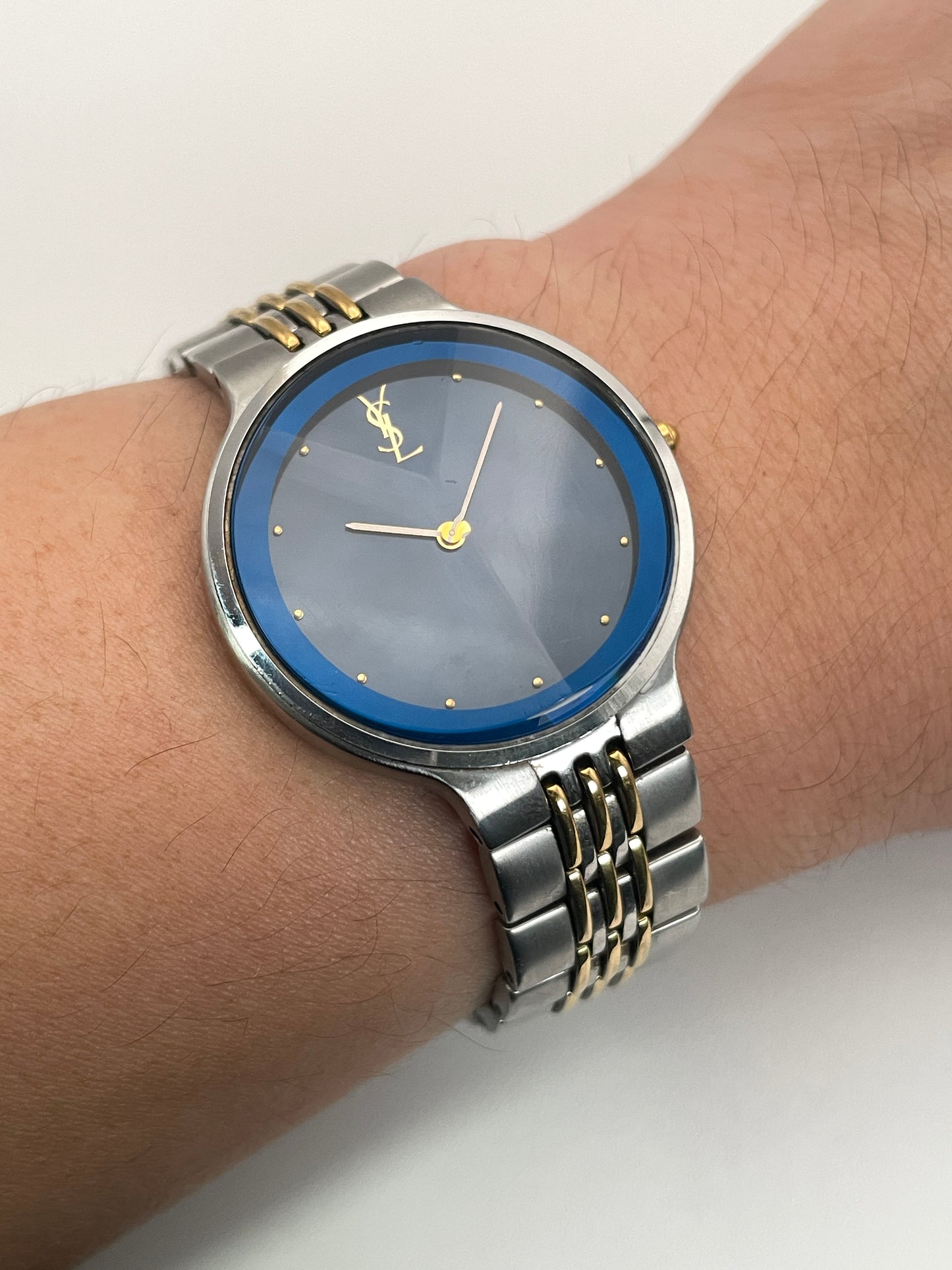 Wrist shot of the YSL La Collection vintage women's watch with a blue sunray dial, faceted crystal, and two-tone bracelet.
