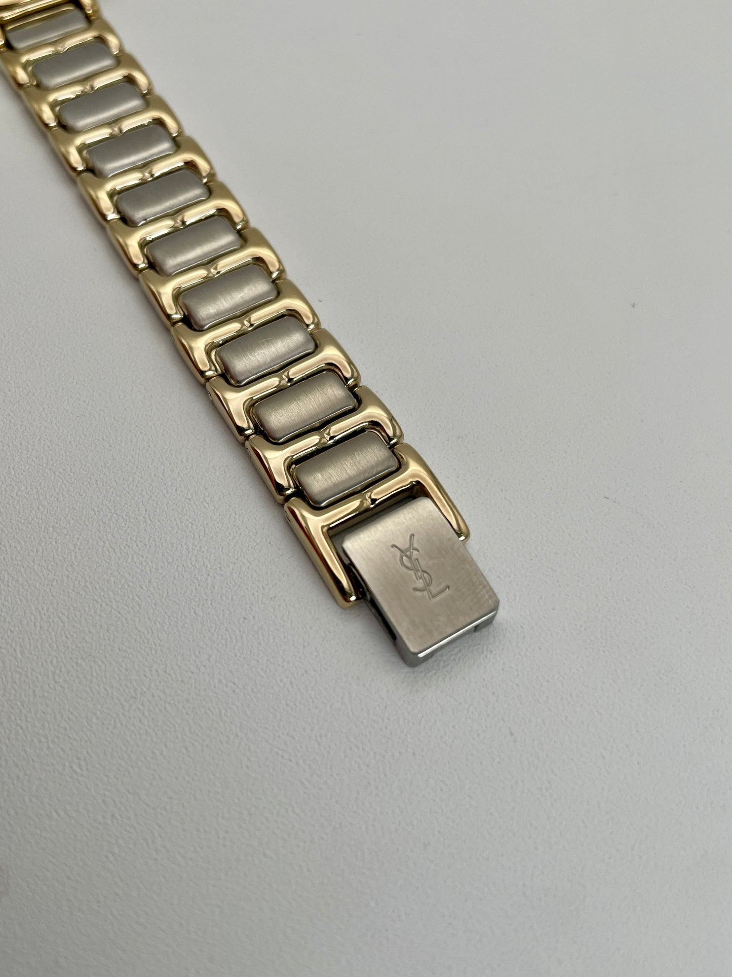 Close-up view of the clasp on Yves Saint Laurent vintage ladies Pour Femme watch's two-tone bracelet.
