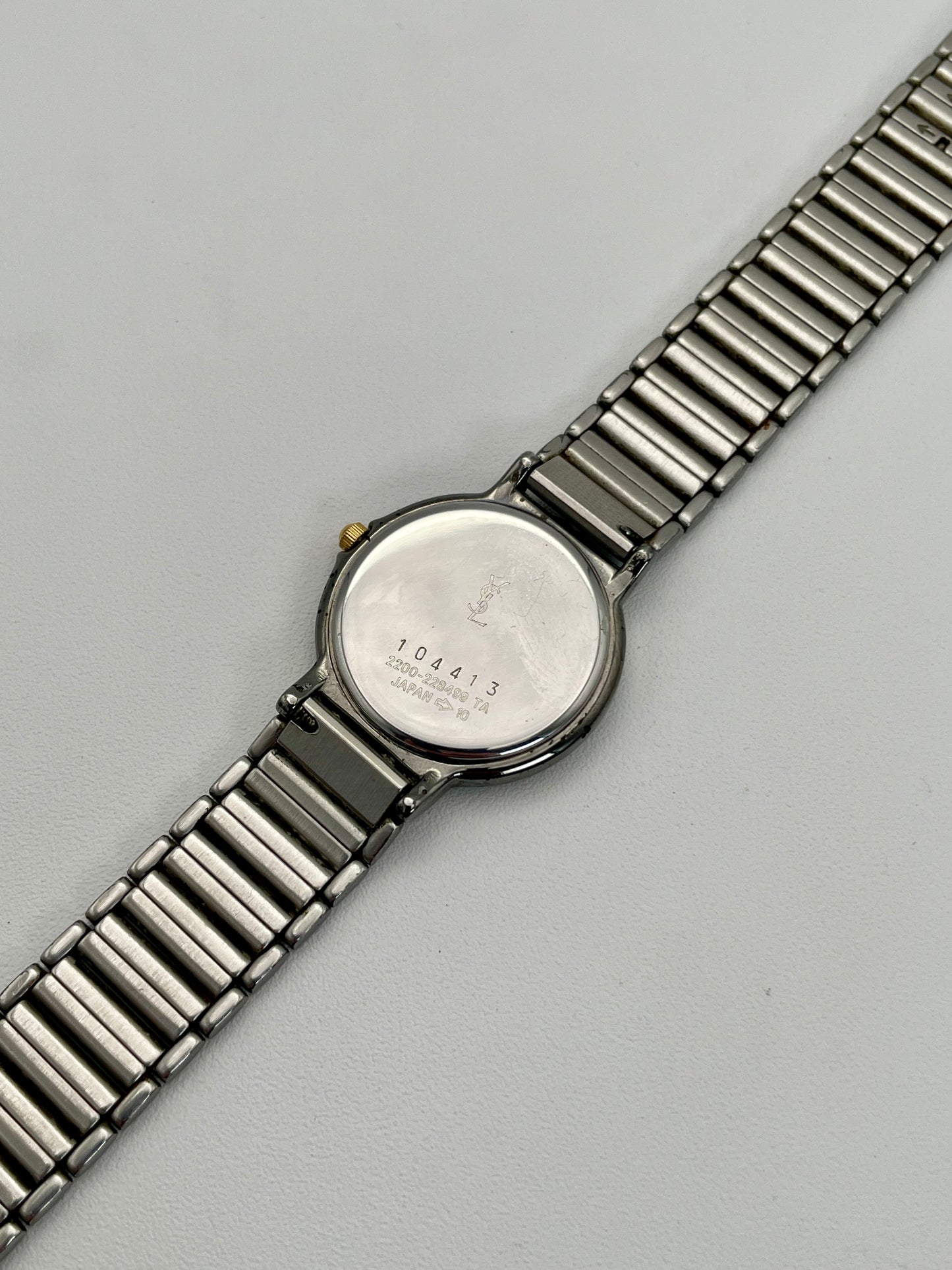Caseback view of the vintage Yves Saint Laurent two-tone watch, featuring engraved details on the stainless steel back.