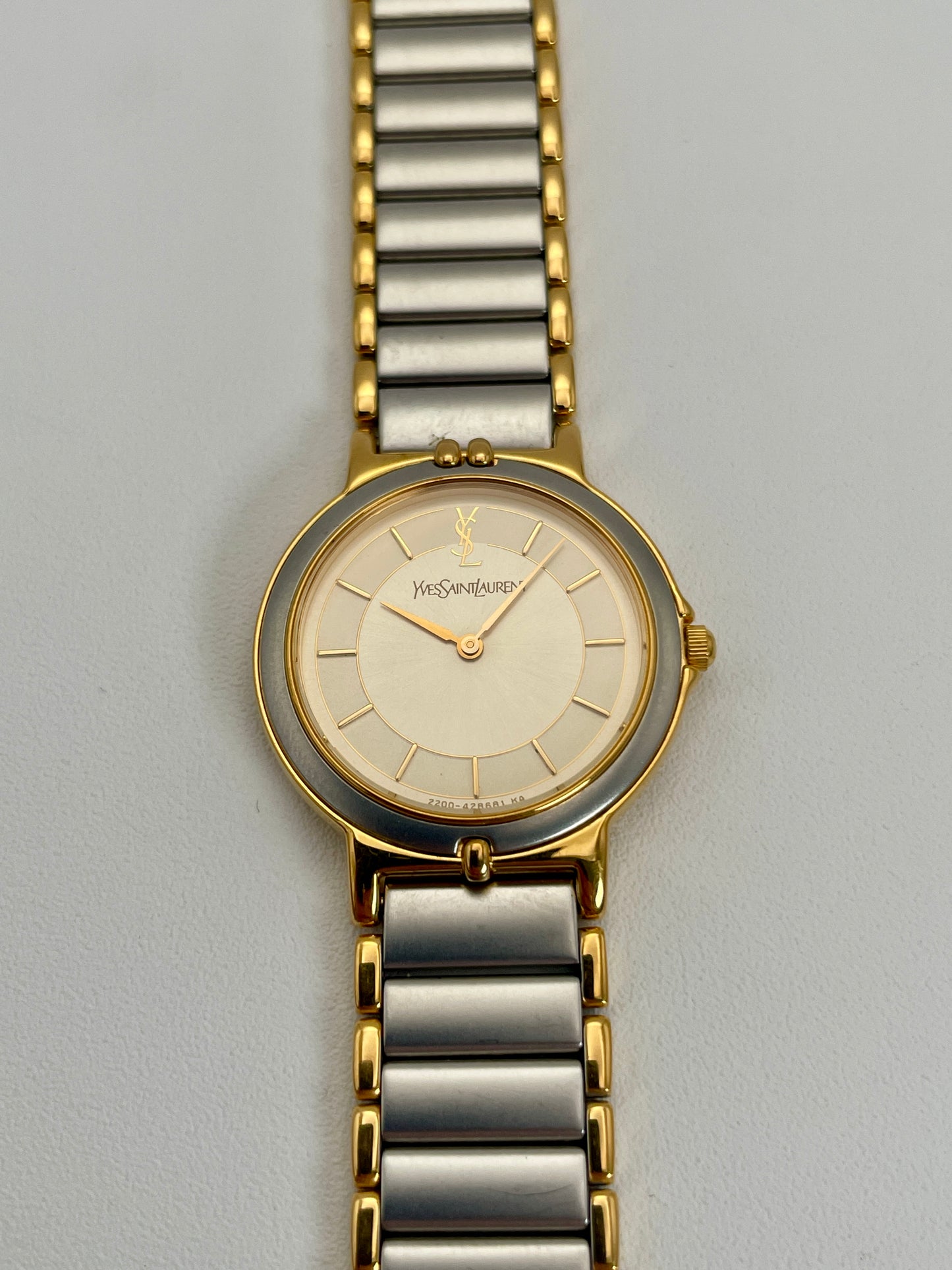 Front view of a YSL vintage two-tone watch featuring a silver dial with gold accents and a two-tone metal bracelet.