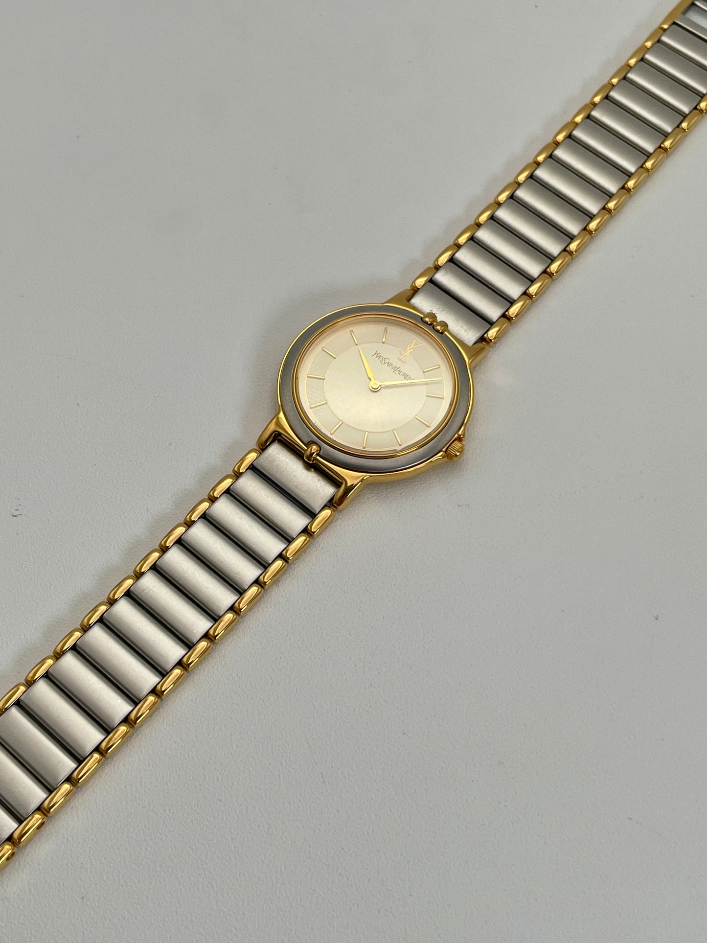 Full view of a YSL vintage two-tone watch with a silver dial, gold accents, and a metal bracelet with gold and silver links.