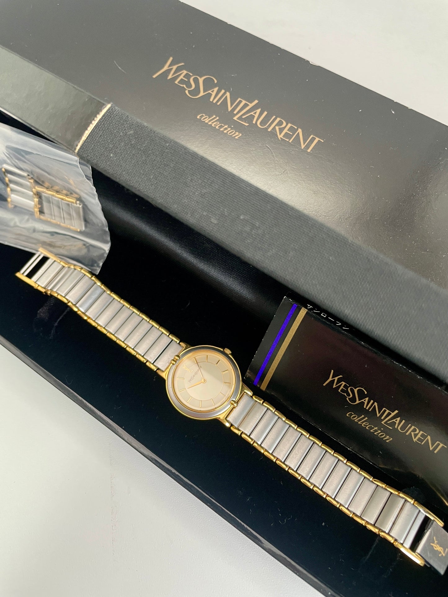Full view of a YSL vintage two-tone watch displayed in its original black YSL Collection box with additional links included.