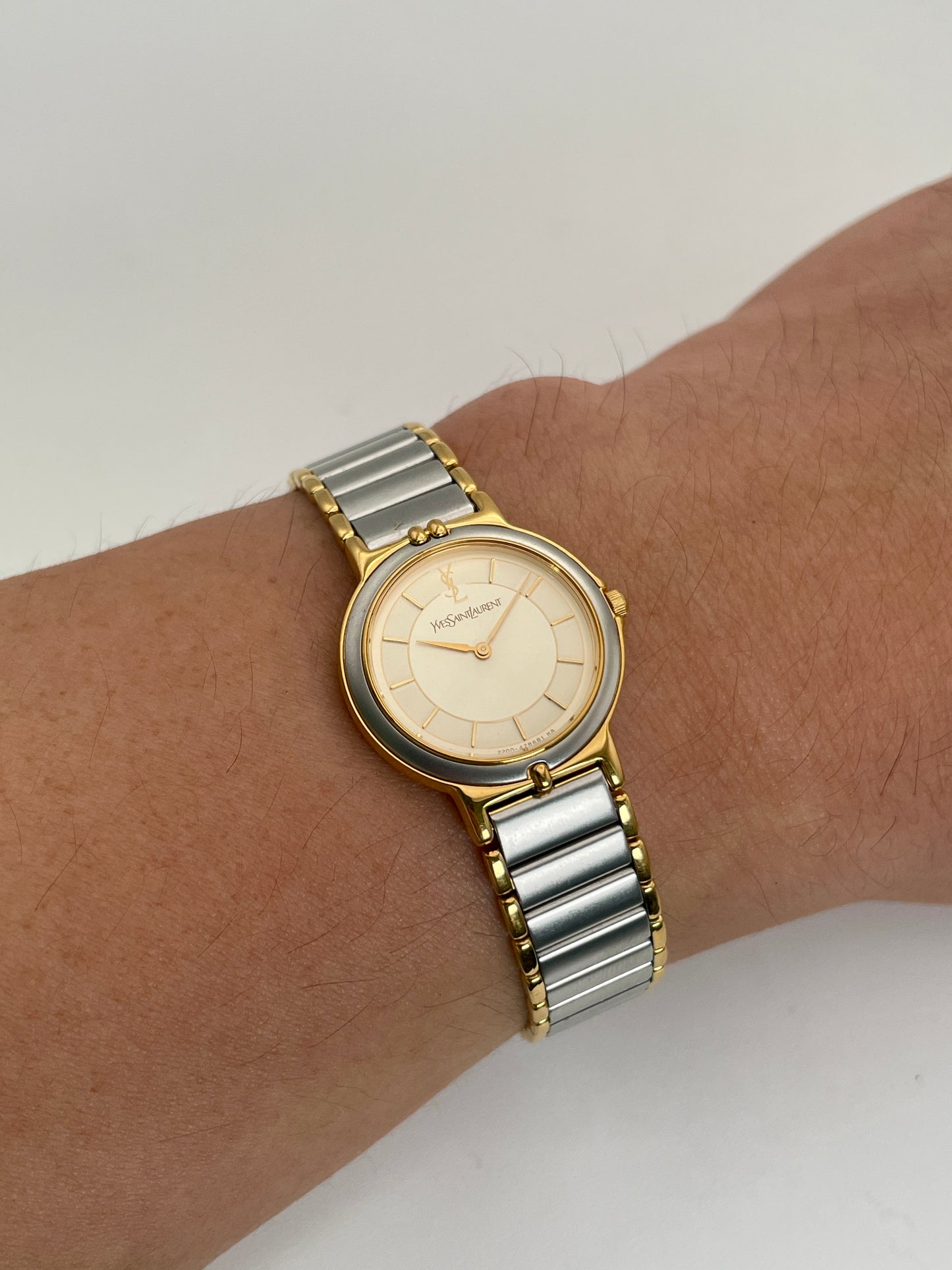 Wrist shot view of a YSL vintage two-tone watch, highlighting its silver dial with gold accents and a two-tone bracelet on the wrist.