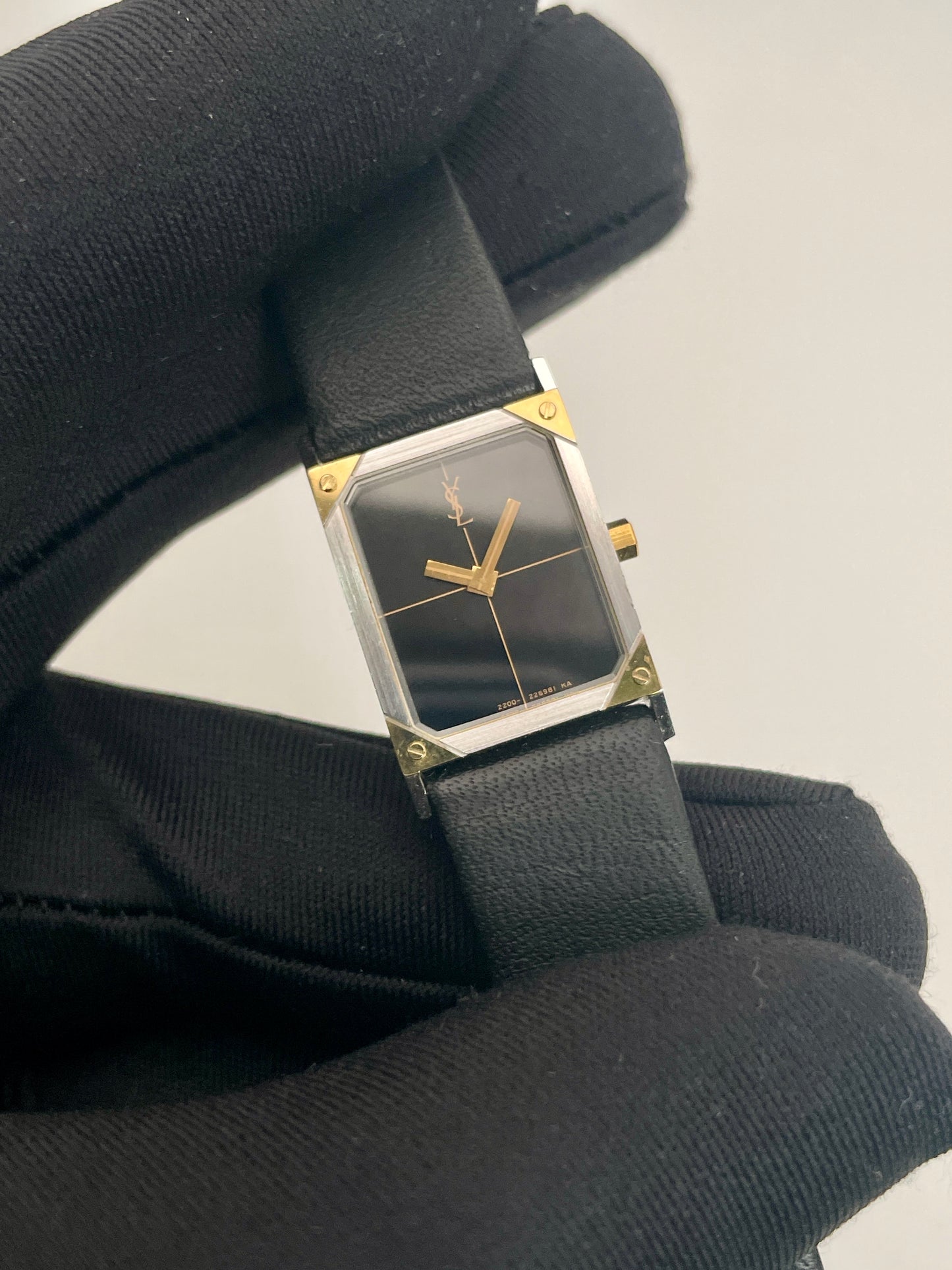 Close-up view of Yves Saint Laurent vintage women's watch highlighting the black dial and gold hands.