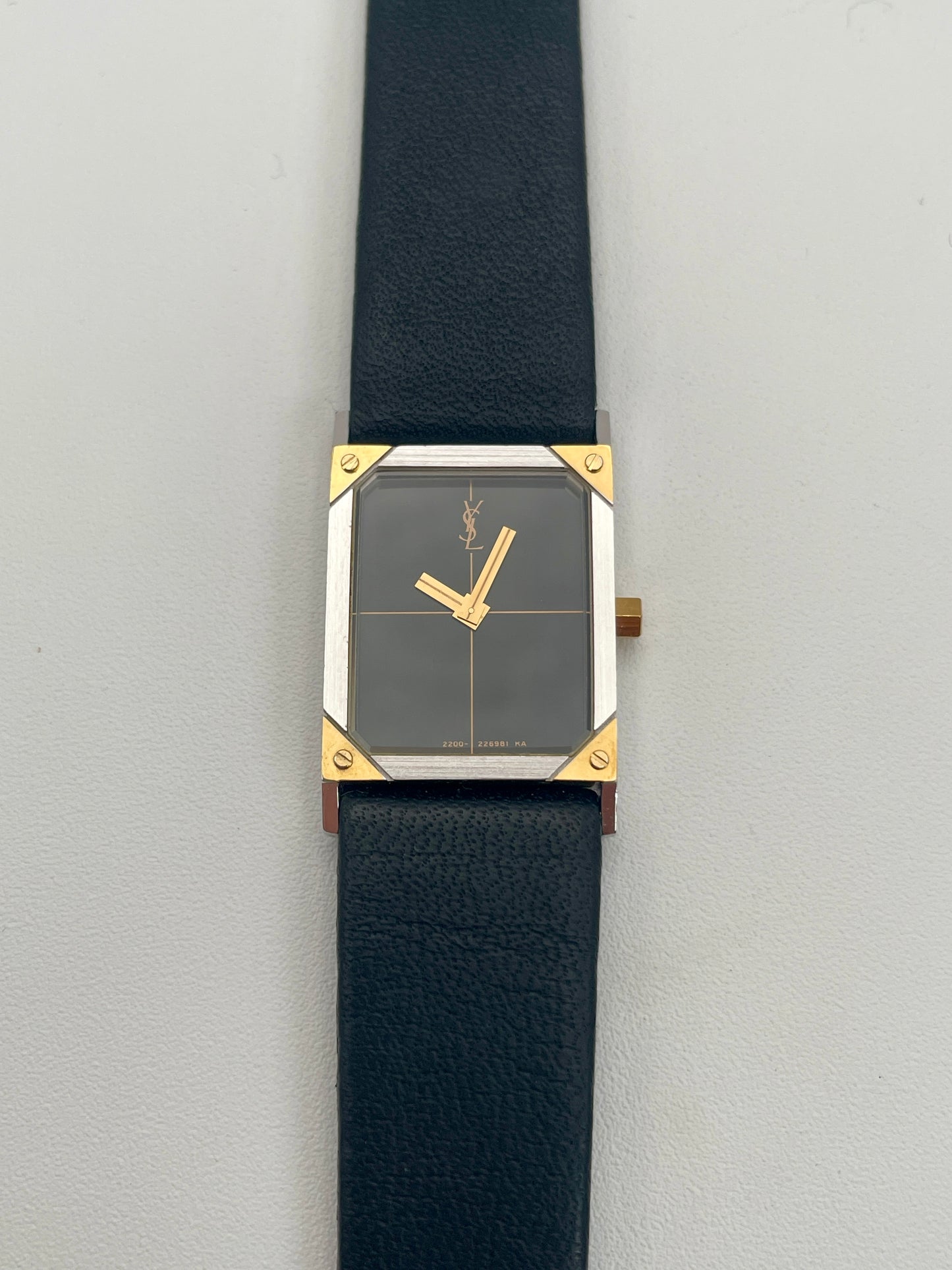 Front view of Yves Saint Laurent vintage women's watch with a steel and gold rectangular case and black leather strap.