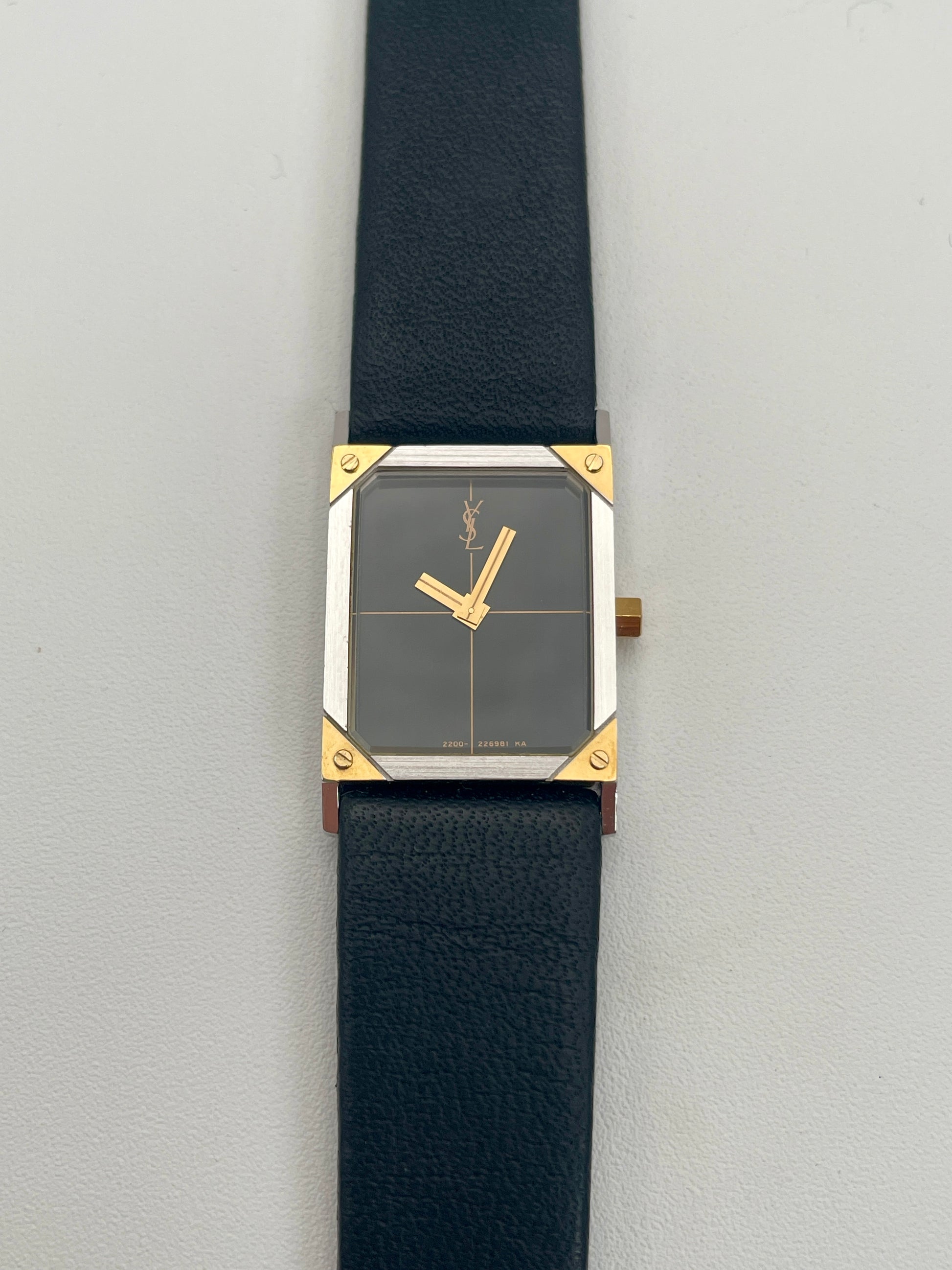 Front view of Yves Saint Laurent vintage women's watch with a steel and gold rectangular case and black leather strap.
