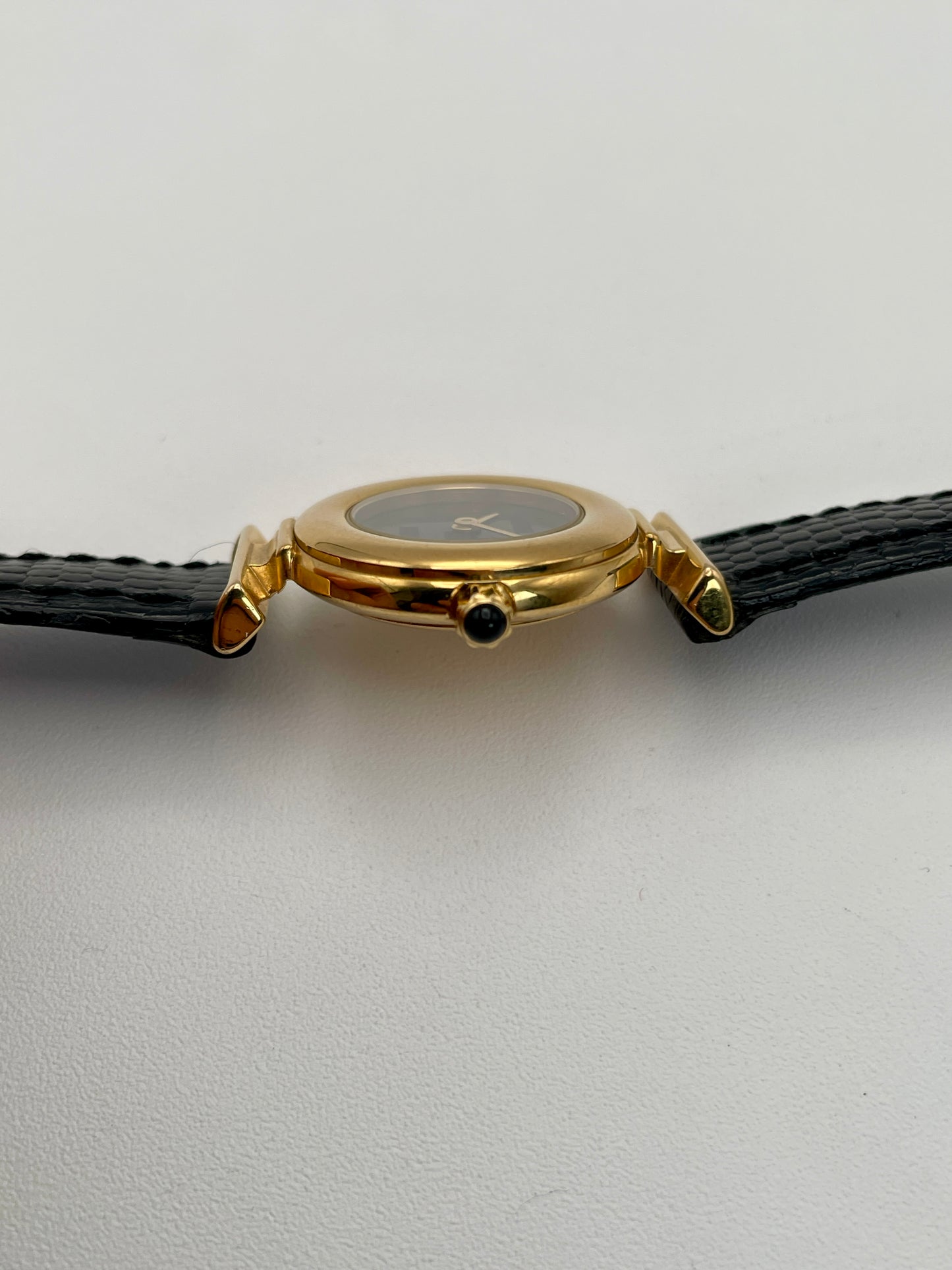 Side crown view of the Fendi 320L watch featuring a gold-tone round case, black leather strap, and a textured crown