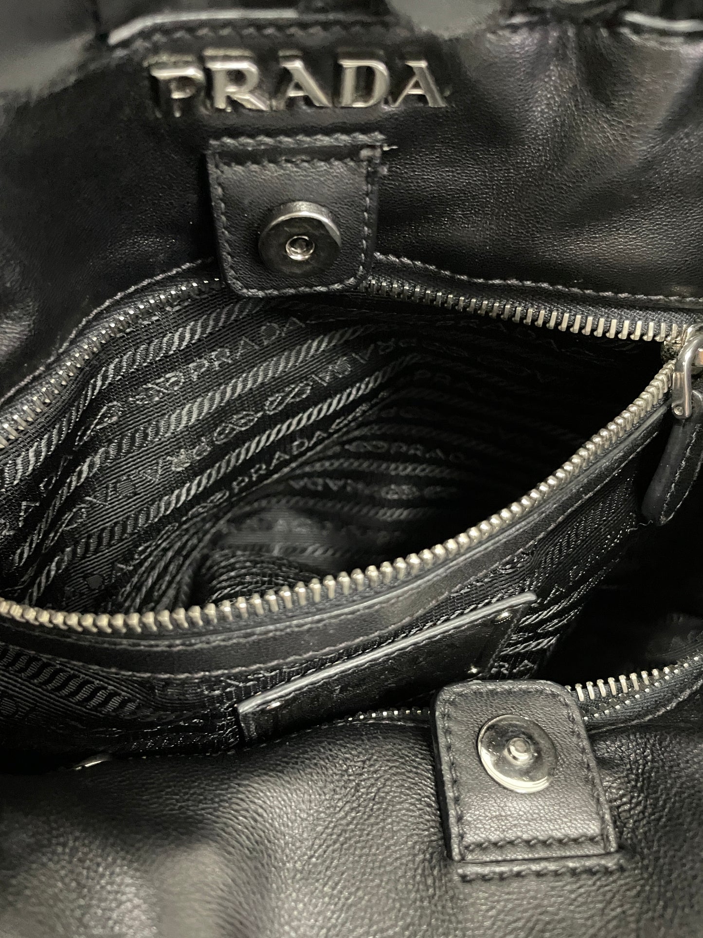 Interior view of the Prada Tessuto Ruffle Bag in black nylon, showcasing its inner pocket and zipper enclosure with the Prada emblem.