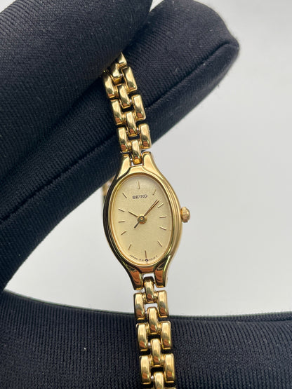 Close-up view of Seiko Oval 1F21-5A00 highlighting the gold-tone finish and champagne dial
