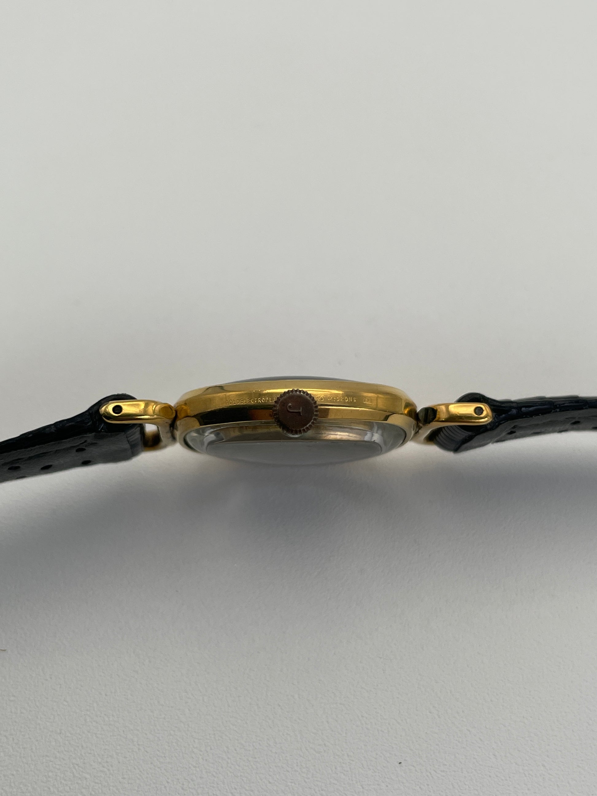 Side view of Juvenia Mystere Skeleton Watch showing the crown and the side profile of the gold case.