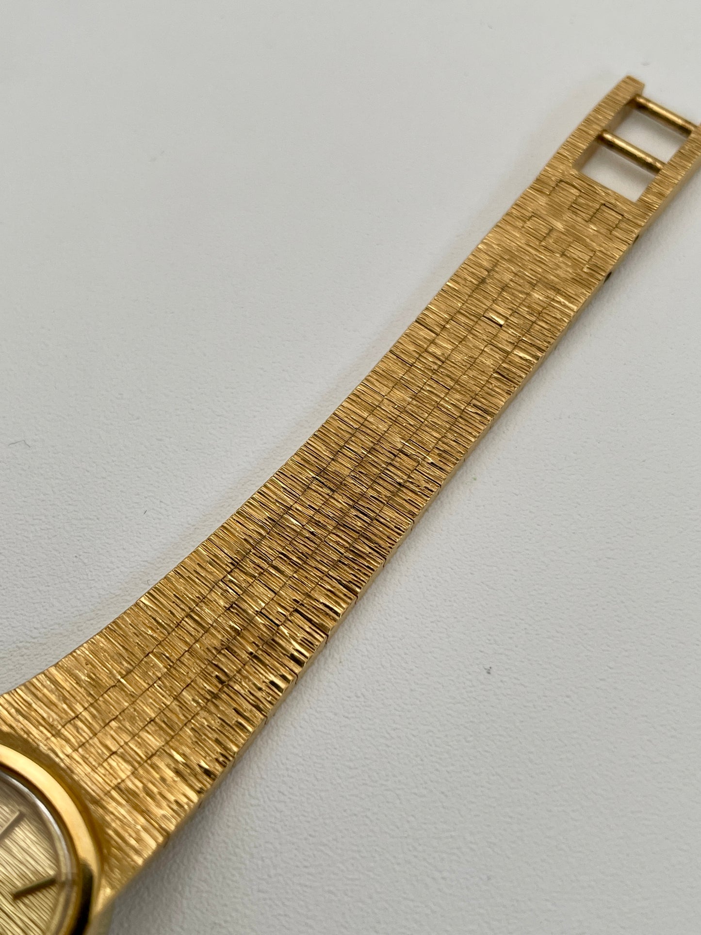 Close-up view of a Tissot Stylist gold dress watch focusing on the gold-tone texture integrated bracelet