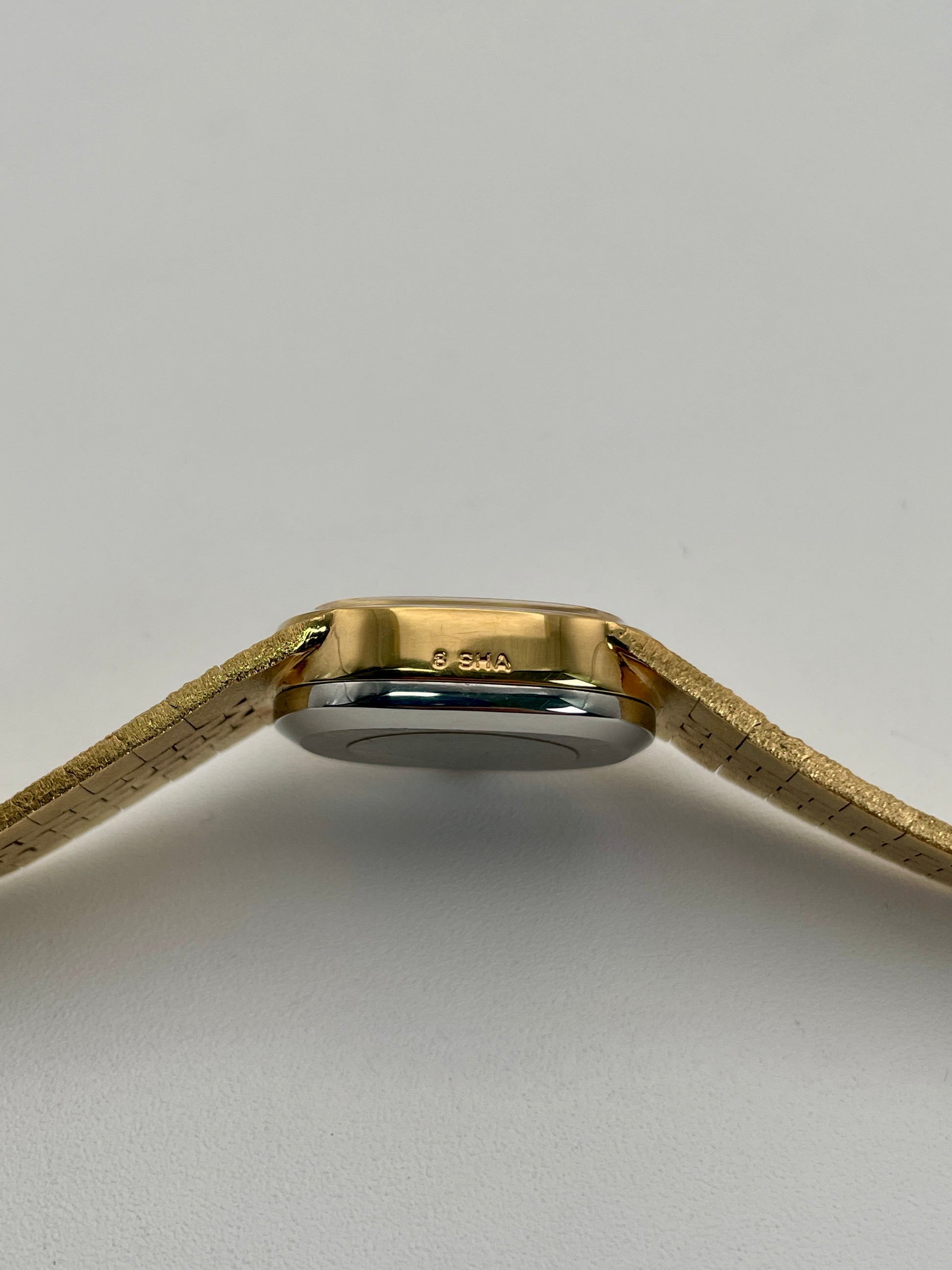 Side case view of a Tissot Stylist gold dress watch displaying the thin profile gold-tone finish and integrated bracelet