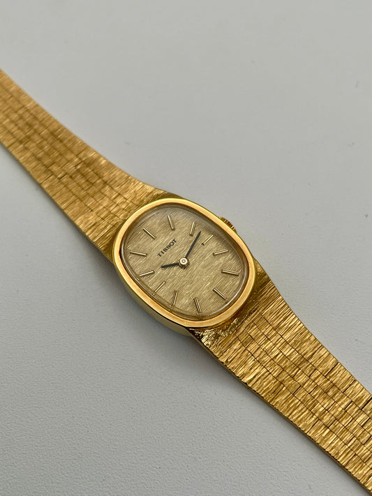 Tissot Stylist gold dress watch showcasing the gold-tone dial, gold oval case, and integrated textured bracelet