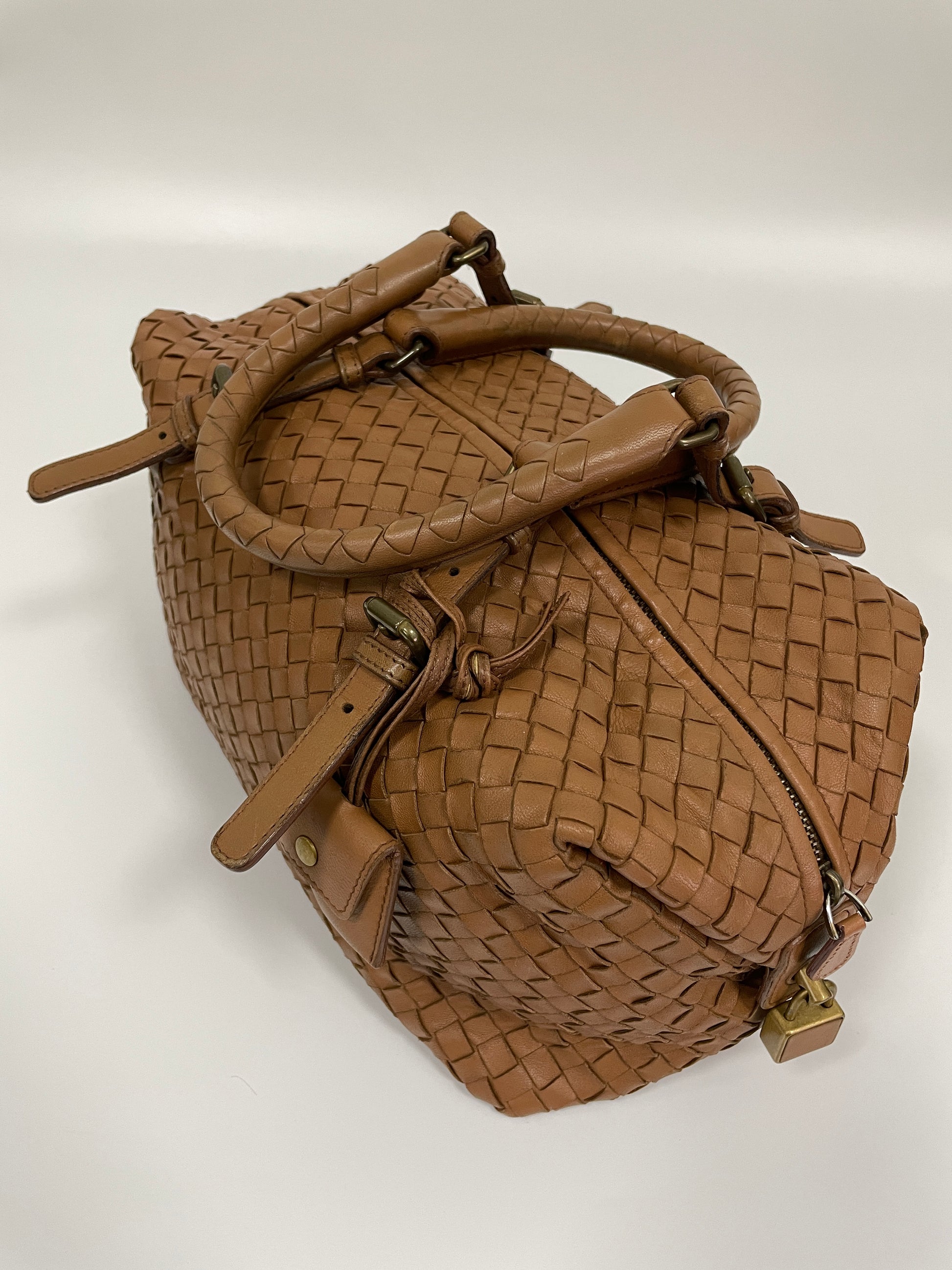 Top view of a Bottega Veneta Intrecciato Montaigne bag in brown leather showcasing the woven leather pattern and the top zipper closure.

