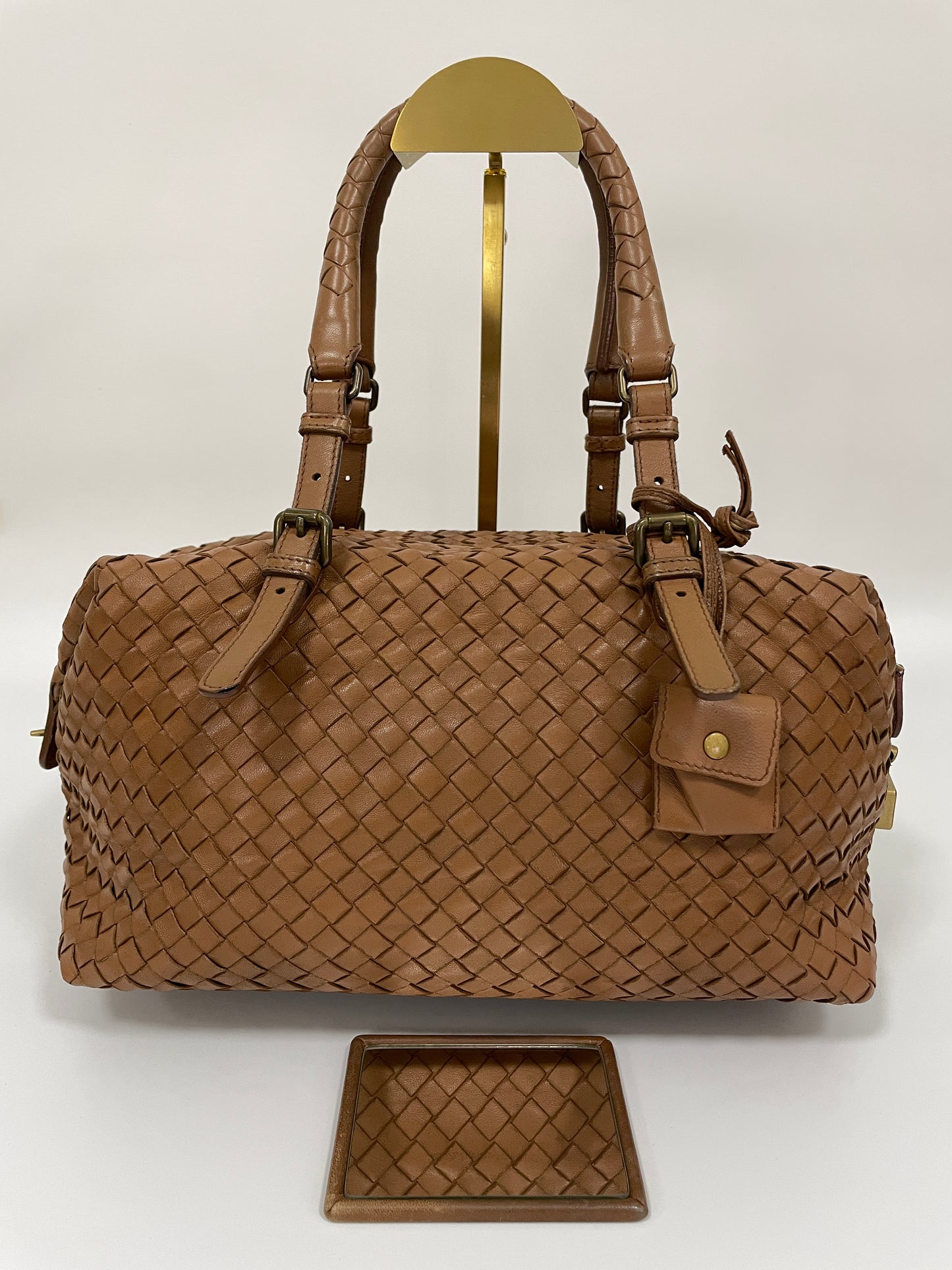 Front view of a Bottega Veneta Intrecciato Montaigne bag in brown leather with dual handles and brass hardware showing the inclusion of mirror.