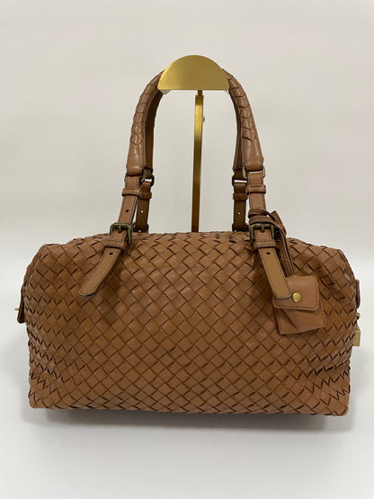 Front view of a Bottega Veneta Intrecciato Montaigne bag in woven brown leather with dual handles and brass hardware.