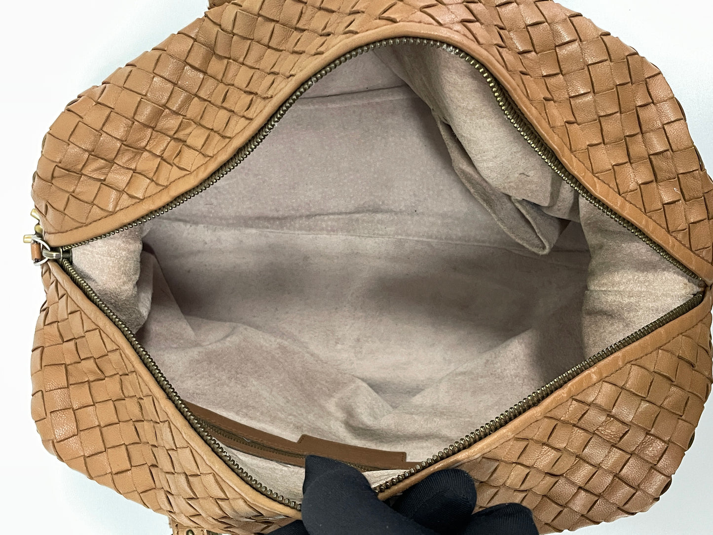 Interior view of a Bottega Veneta Intrecciato Montaigne bag in brown leather showing the spacious beige lining and zipper compartment.