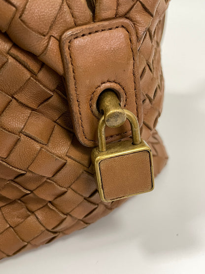 Close-up view of the brass lock detail on the Bottega Veneta Intrecciato Montaigne bag in brown leather.