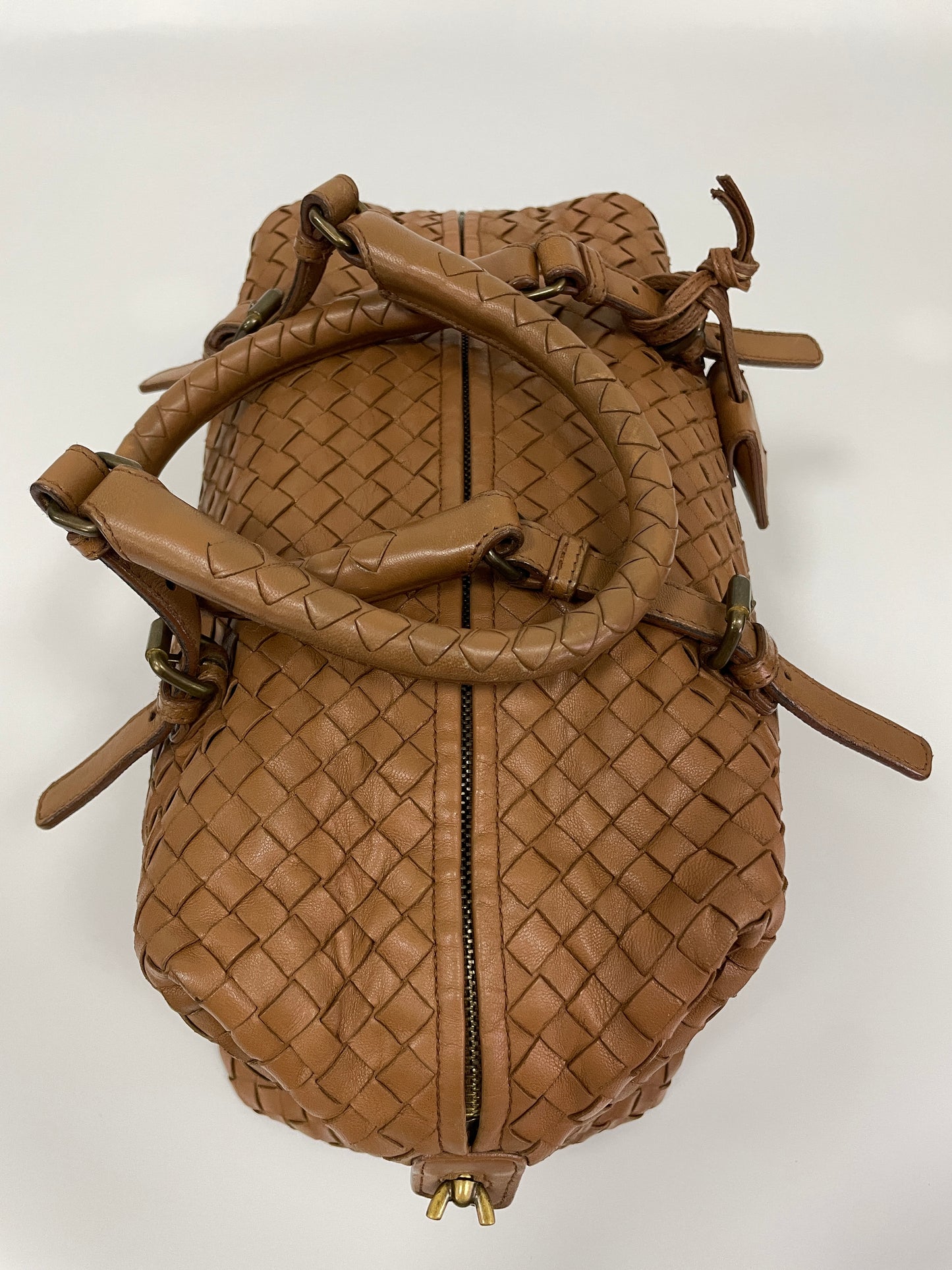 Top view of a Bottega Veneta Intrecciato Montaigne bag in brown leather showcasing the woven leather pattern and the top zipper closure.