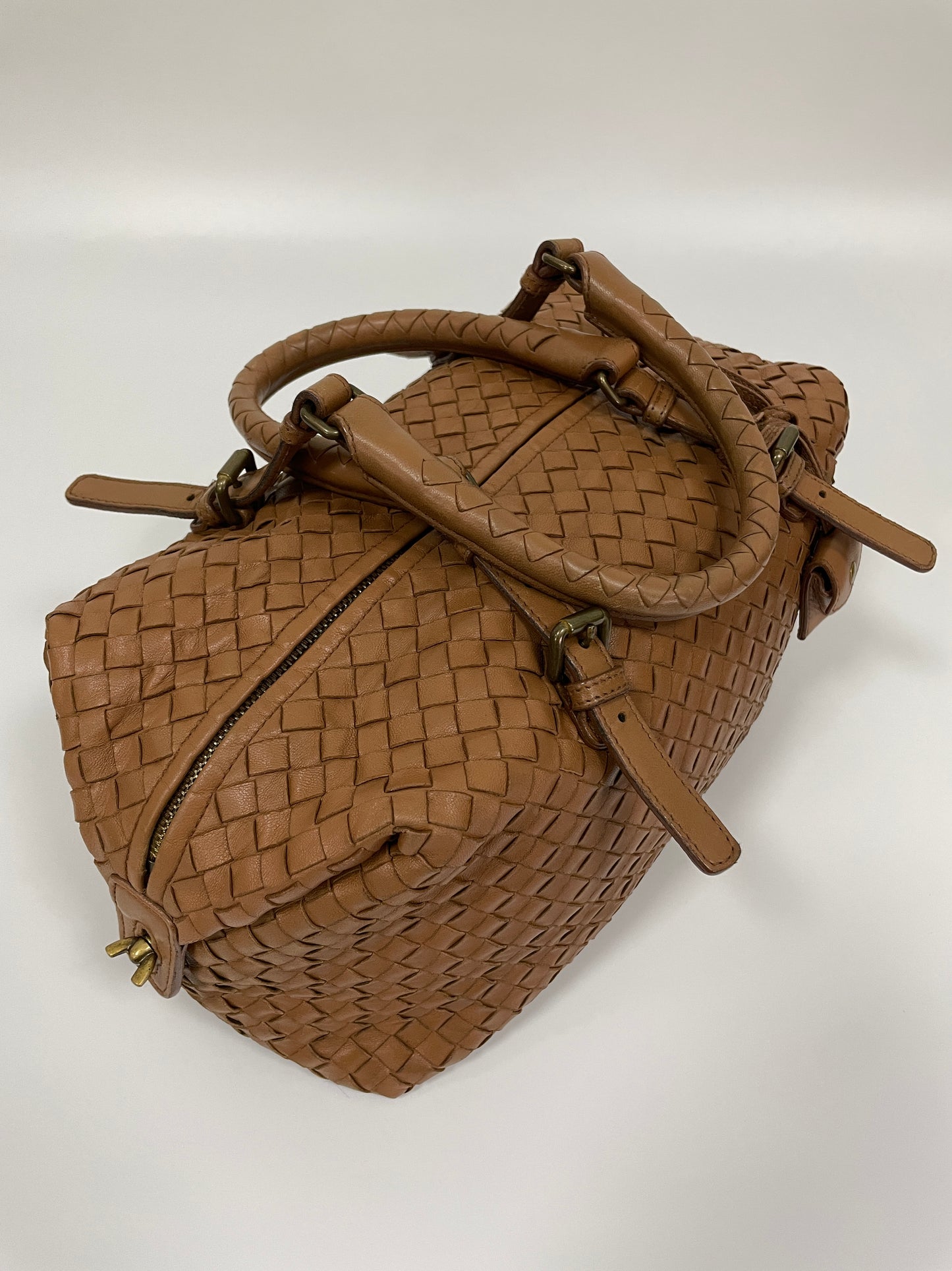 Top view of a Bottega Veneta Intrecciato Montaigne bag in brown leather showcasing the woven leather pattern and the top zipper closure.
