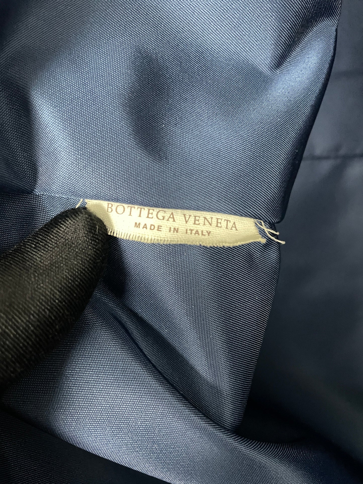 Close-up of the Bottega Veneta brand tag inside the Bottega Veneta Intrecciolusion Mirage Butterfly Tote Bag in blue, with "Made in Italy" inscription.