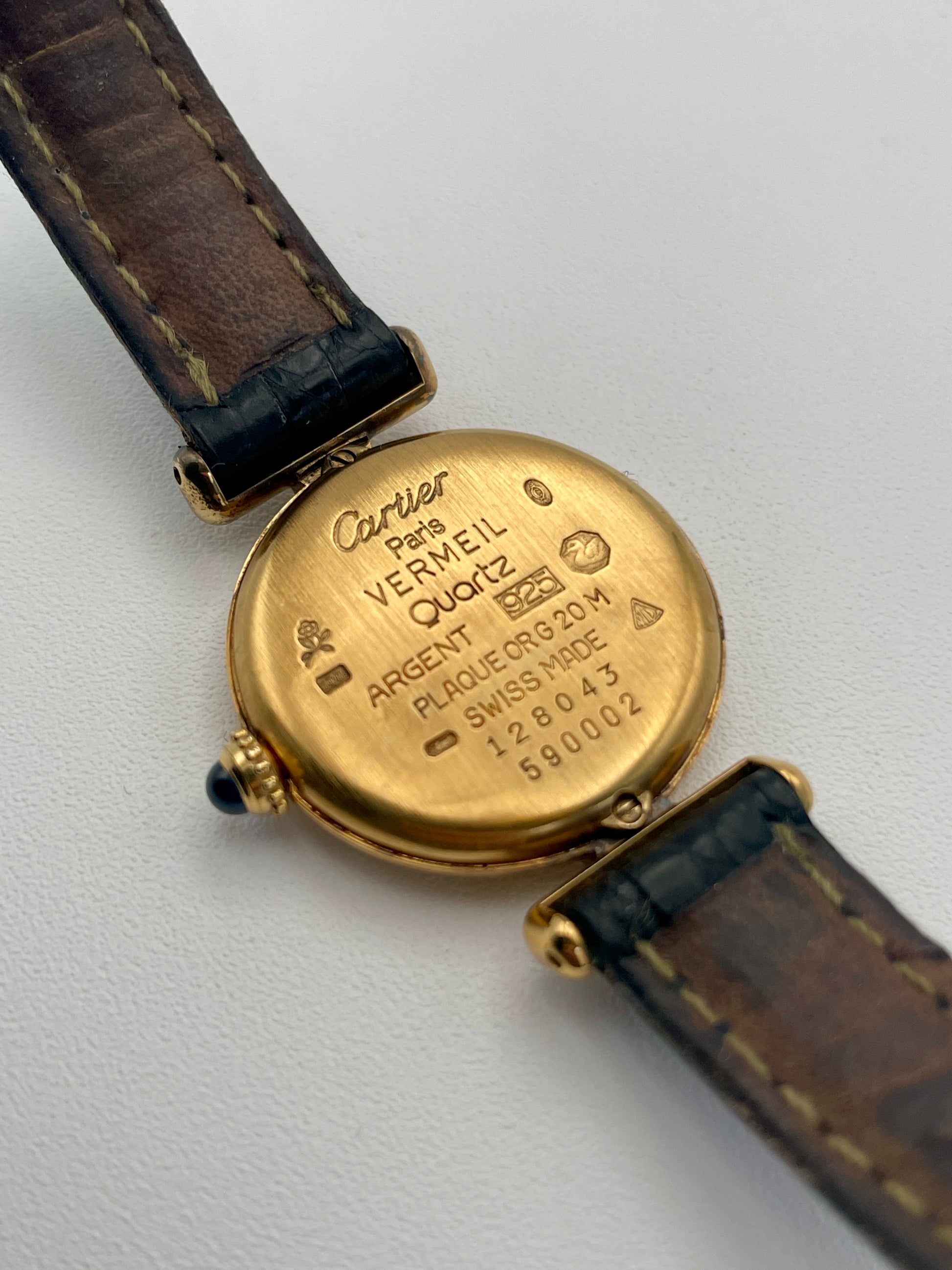 Caseback view of Cartier Colisée Vermeil watch showcasing engraved details on the gold-tone round case with a black leather strap