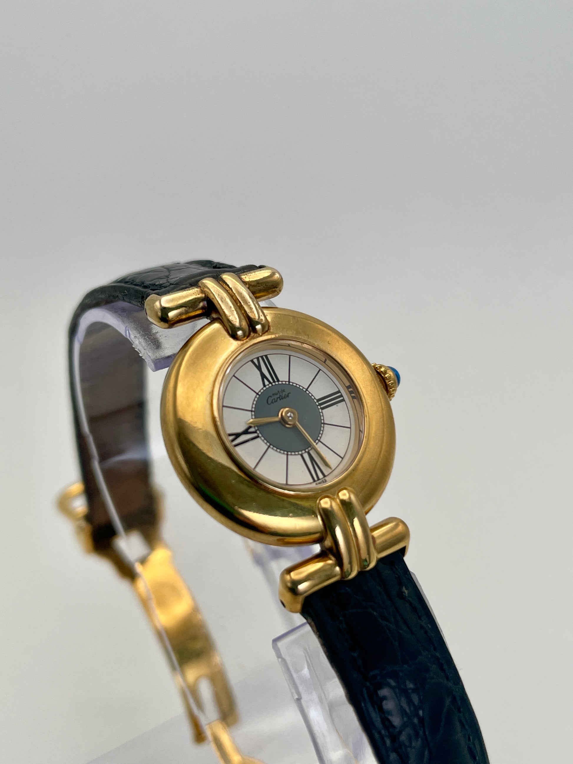 Cartier Colisée Vermeil watch with a gold-tone round case, Roman numeral sector dial, and black leather strap.