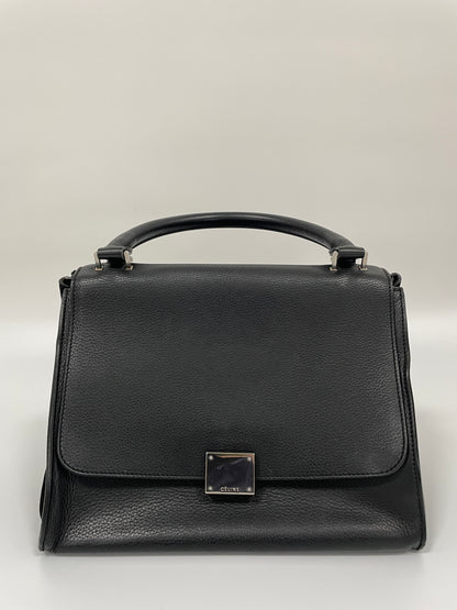 Celine Trapeze Bag in black leather with velvet trim, featuring a front flap and a silver-tone clasp, with its side wings and flaps tucked.