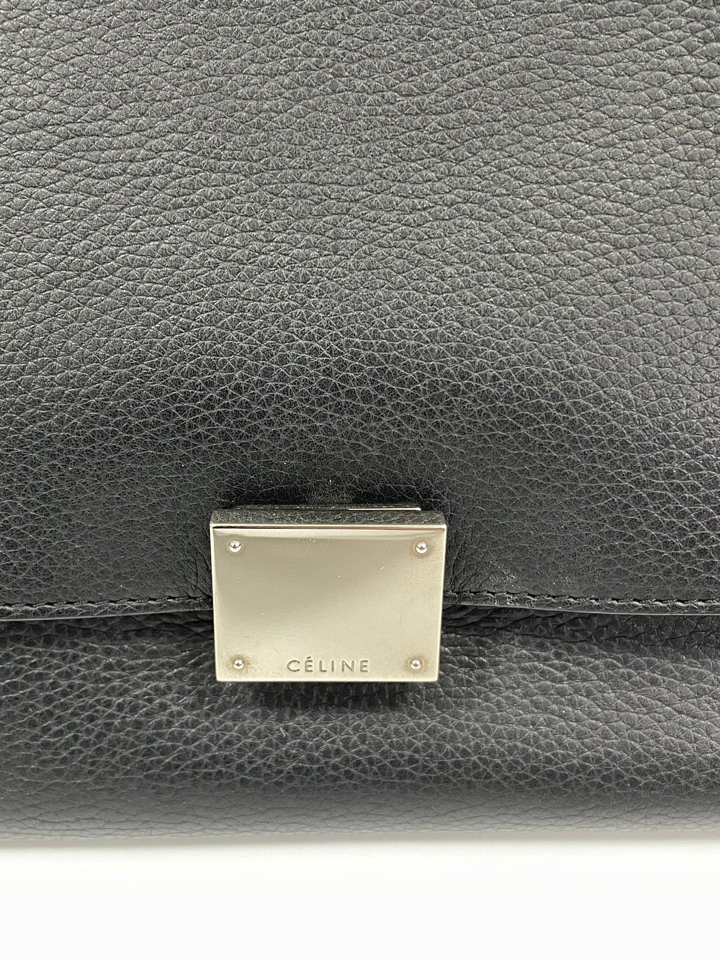 Close-up of the Celine Trapeze Bag's silver-tone clasp on the black leather flap, showing the "Celine" logo engraved.