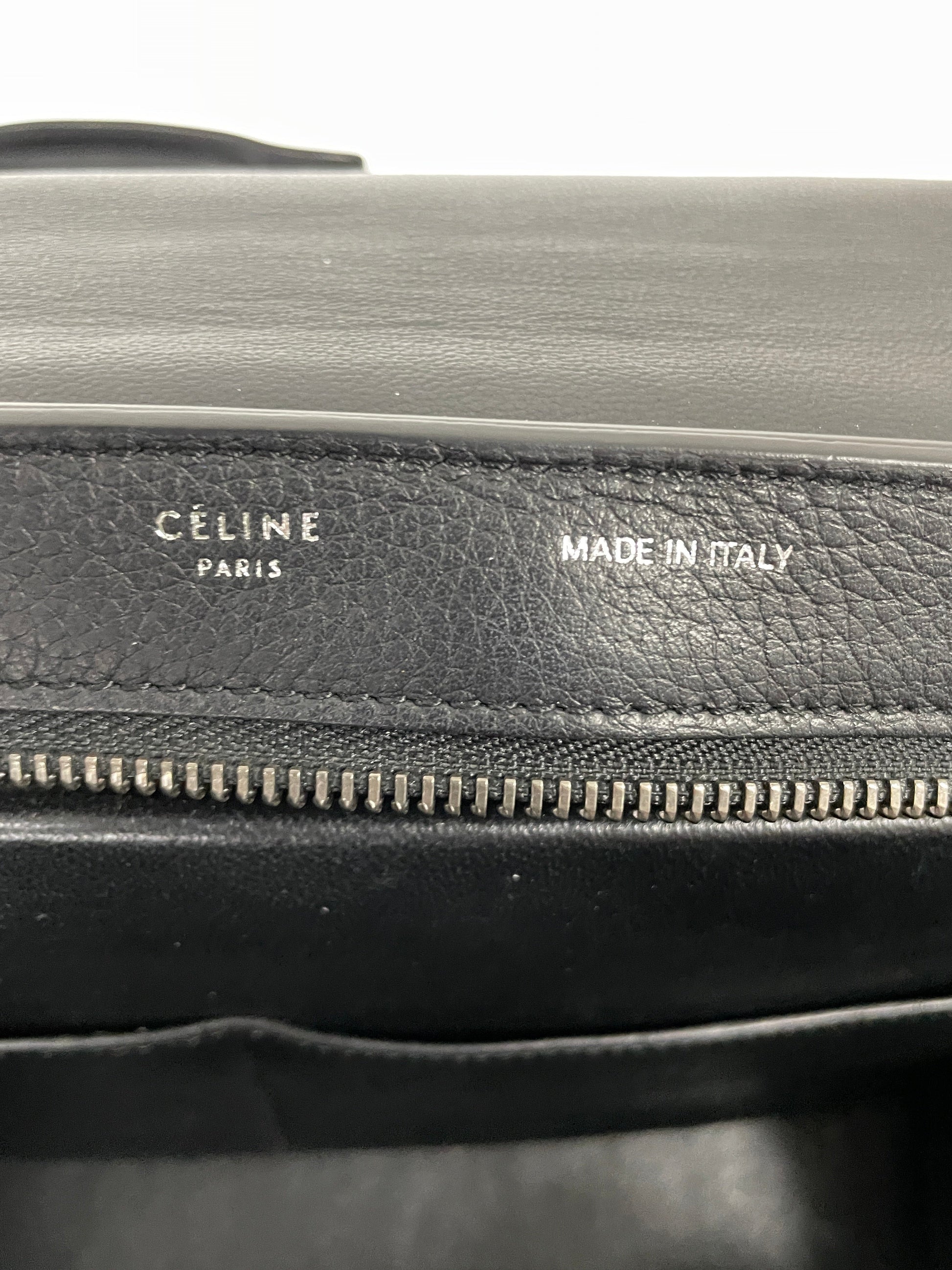 Close up view of the Celine Trapeze bag in black leather and velvet trim, showing the printed Celine Paris label and Made in Italy print.