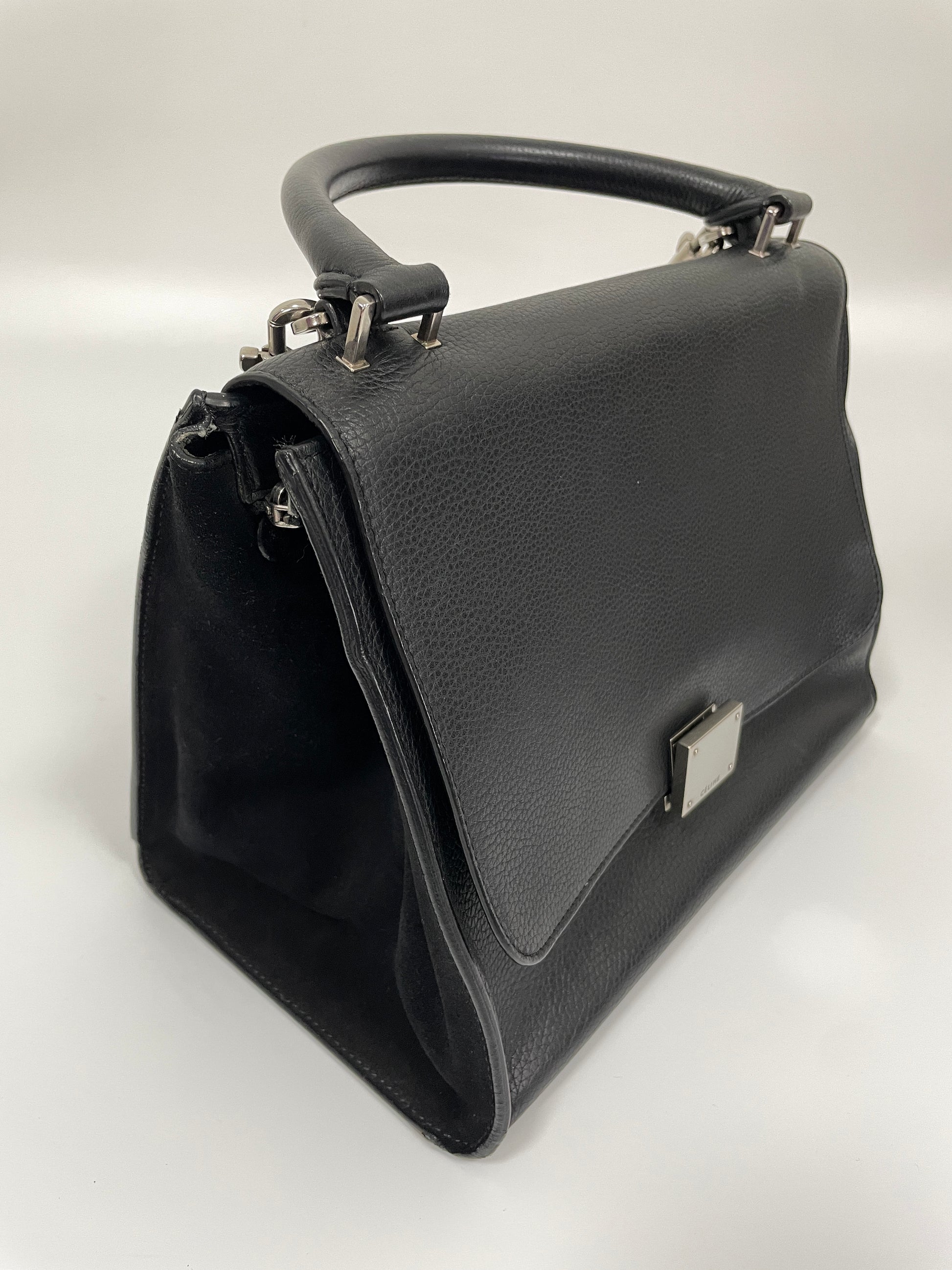 Celine Trapeze Bag in black leather and velvet trim shown from a diagonal angle, highlighting shape of the bag when its wing panels are closed.