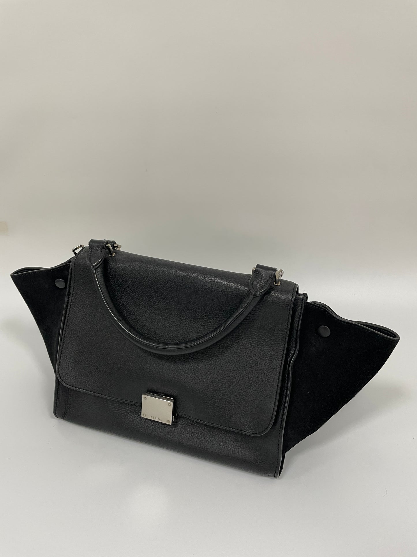 Celine Trapeze Bag in black leather and velvet trim shown from a diagonal angle, highlighting the front and side panels.