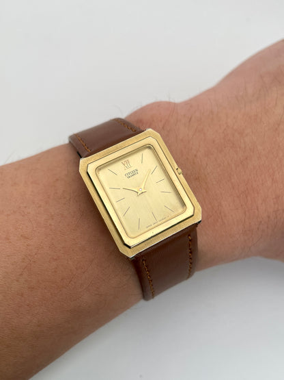 Citizen Tank Vintage Watch in gold worn on the wrist with a brown leather strap.