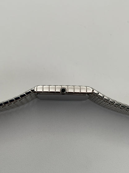 Side view of a Credor 2F70 bracelet watch, showcasing the silver-tone rectangular case, gold-tone bezel, and the side crown against the textured mesh bracelet.