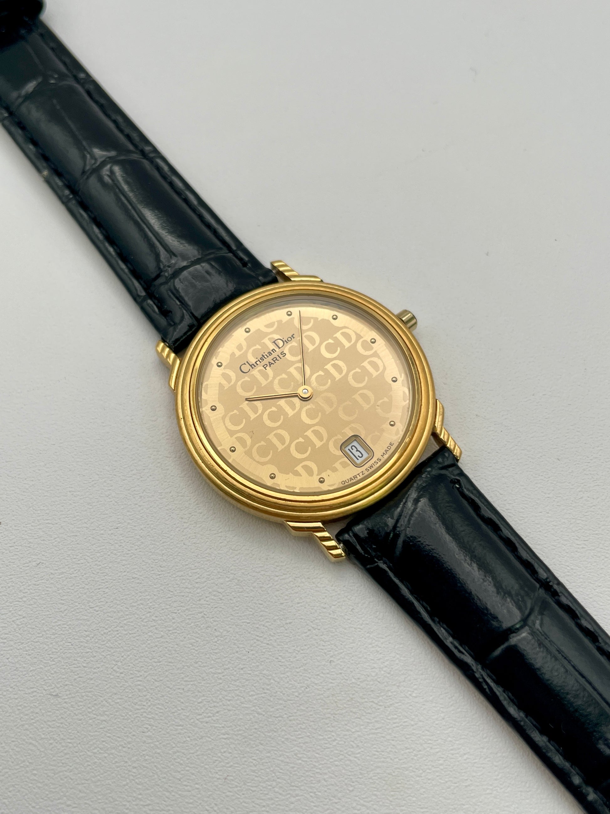 Christian Dior 45.122 vintage women's watch in gold-tone case with CD monogram dial and black leather strap, front view
