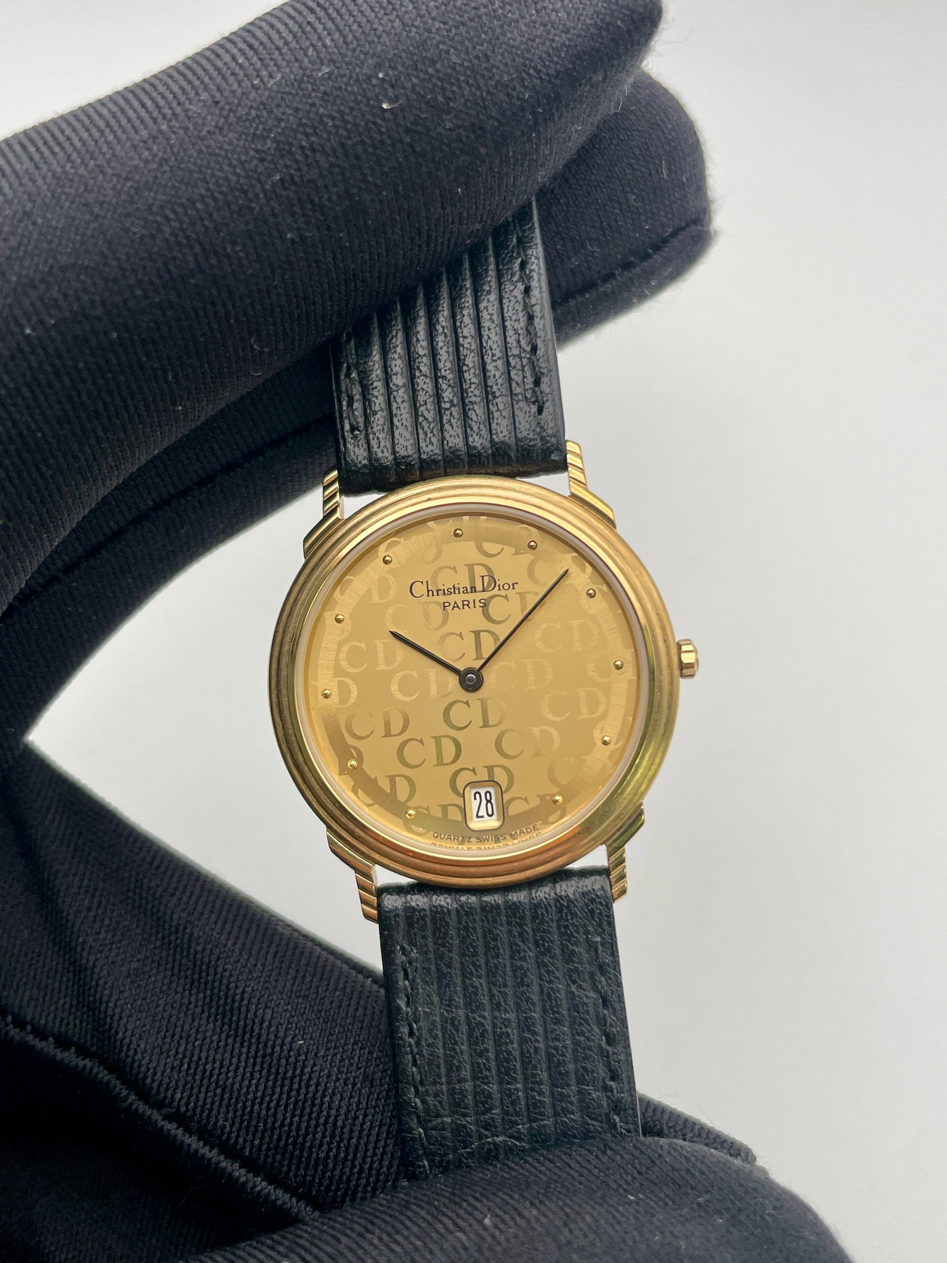 Close-up view of Christian Dior 45.122 vintage watch with gold case, CD monogram dial, and ribbed strap
