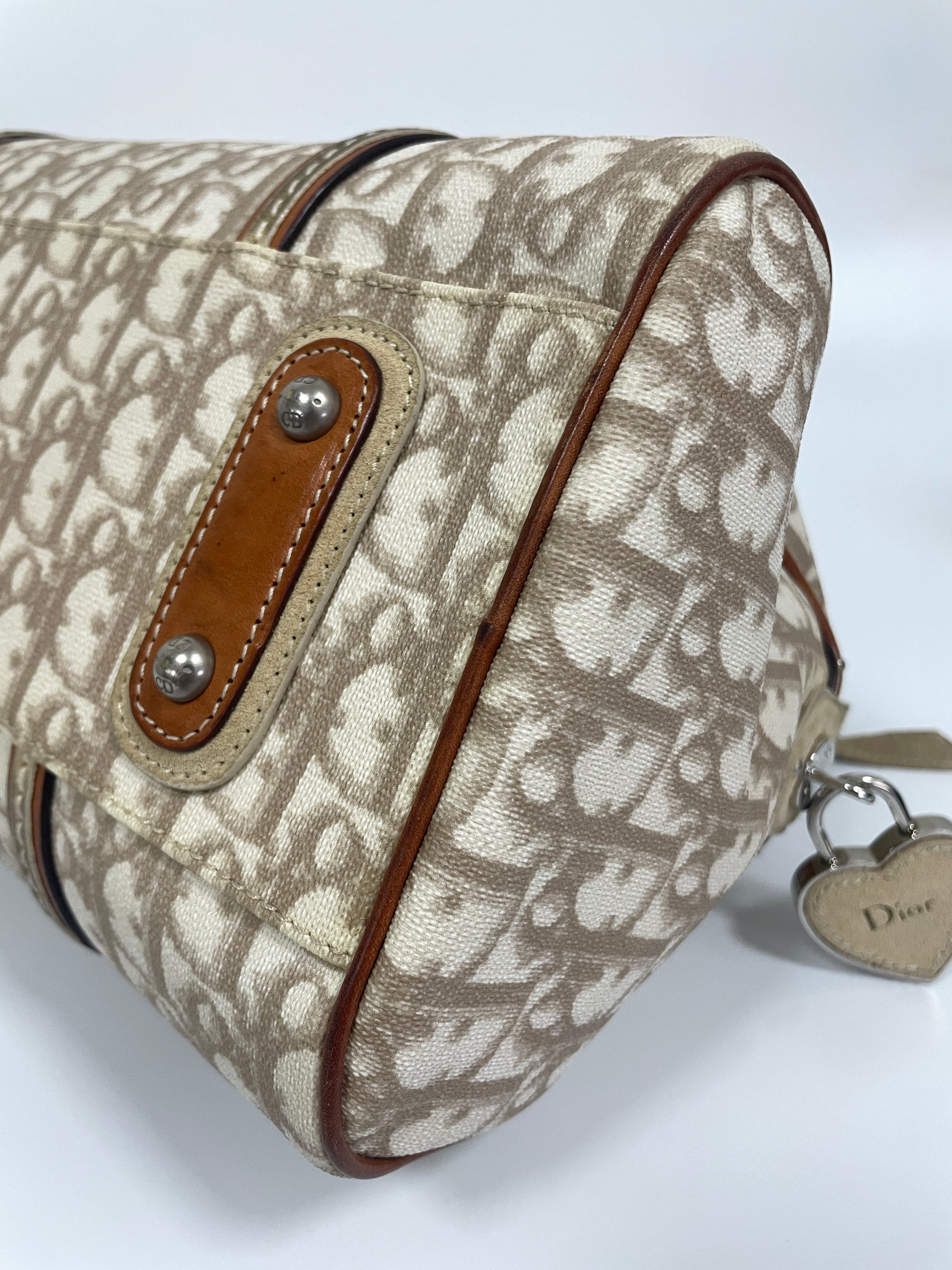 Bottom corner view of Christian Dior Trotter Romantique bag in beige leather and canvas showing the reinforced leather corners.