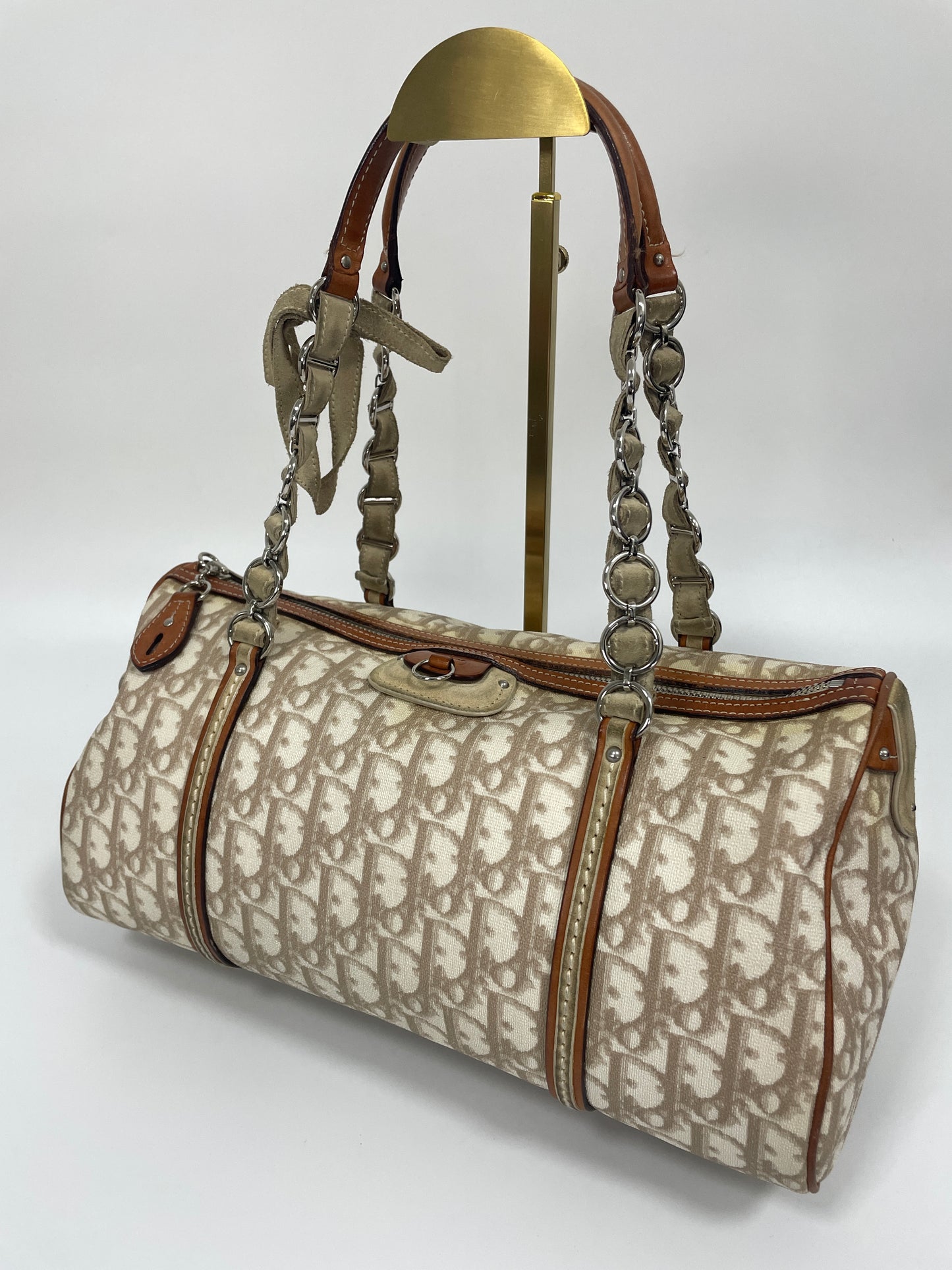 Diagonal view of Christian Dior Trotter Romantique bag in beige leather and canvas with metal chain accents and leather straps.