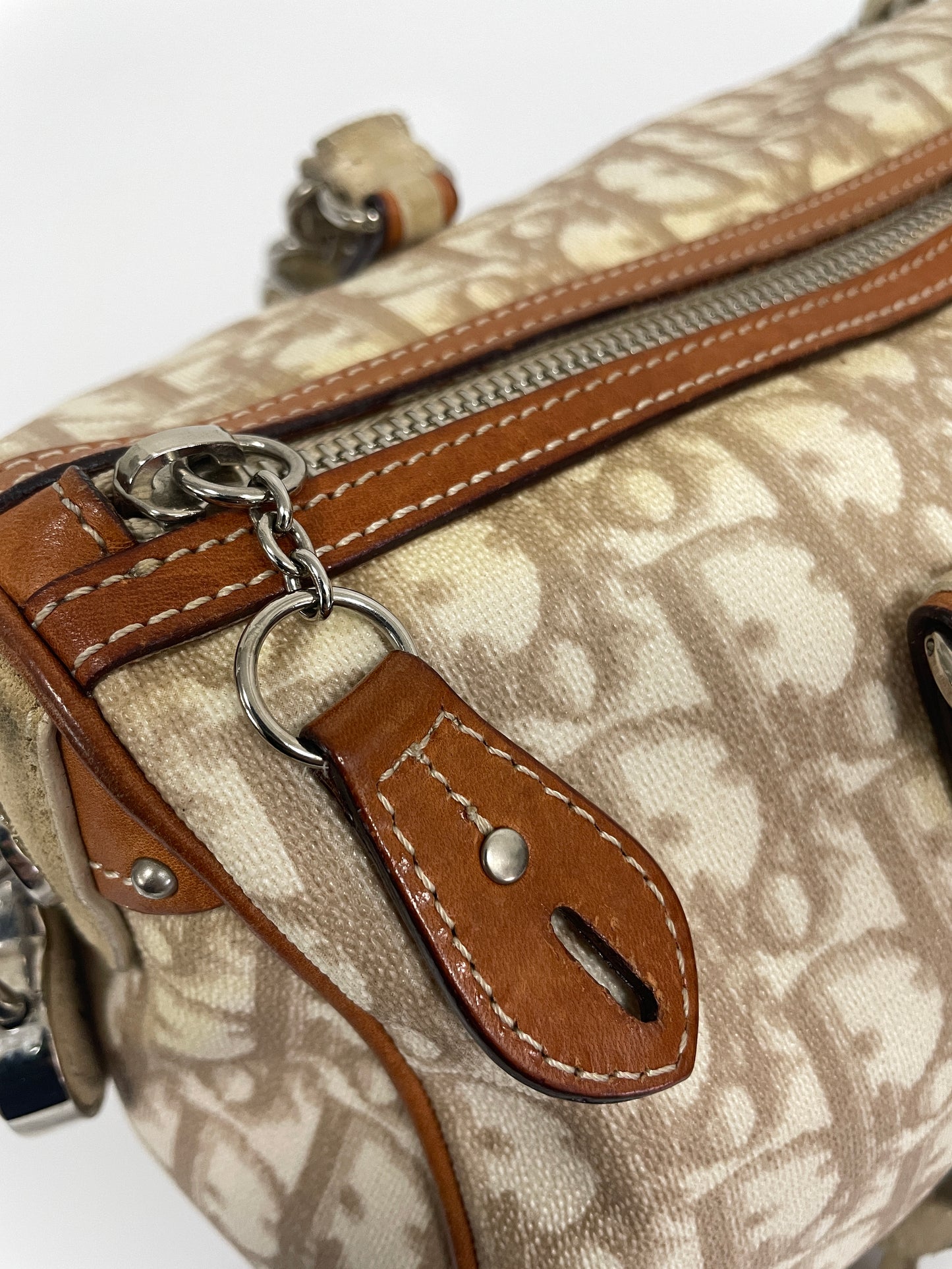 Close-up of the zipper and leather detail on the Christian Dior Trotter Romantique Bag in beige leather and canvas.