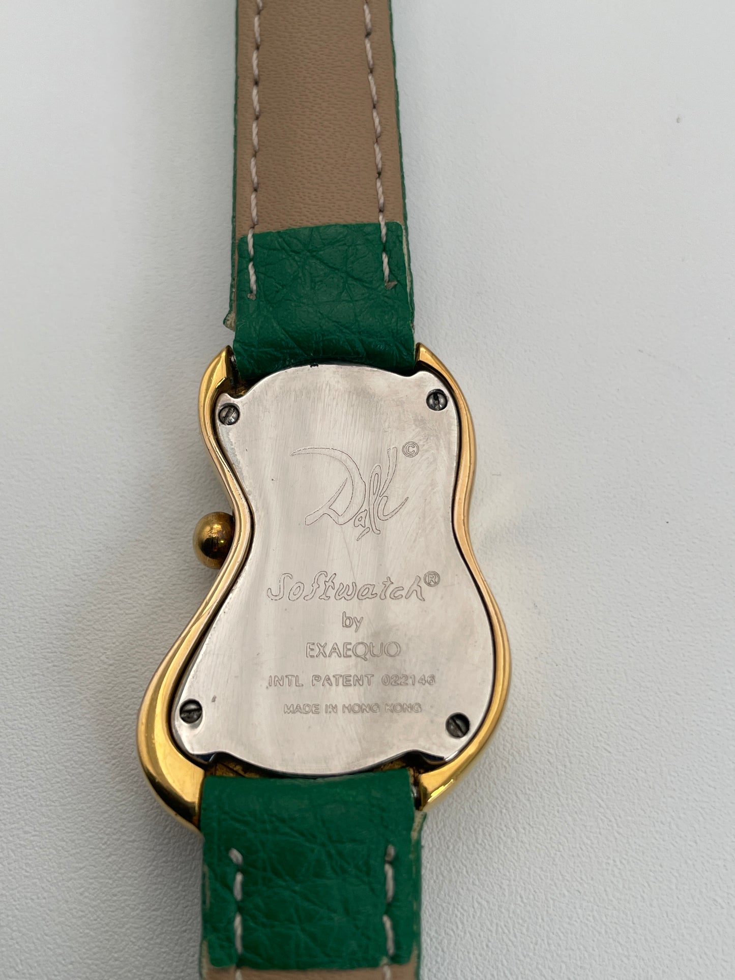 Caseback view of an Exaequo Salvador Dali Softwatch showing the engraved case back and green leather strap.