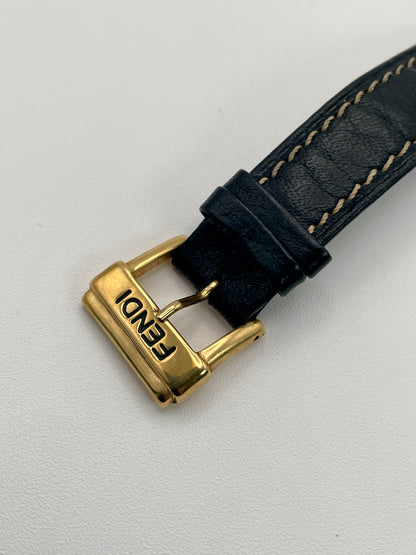 Close-up of the signed Fendi gold-tone buckle attached to the textured black leather strap.