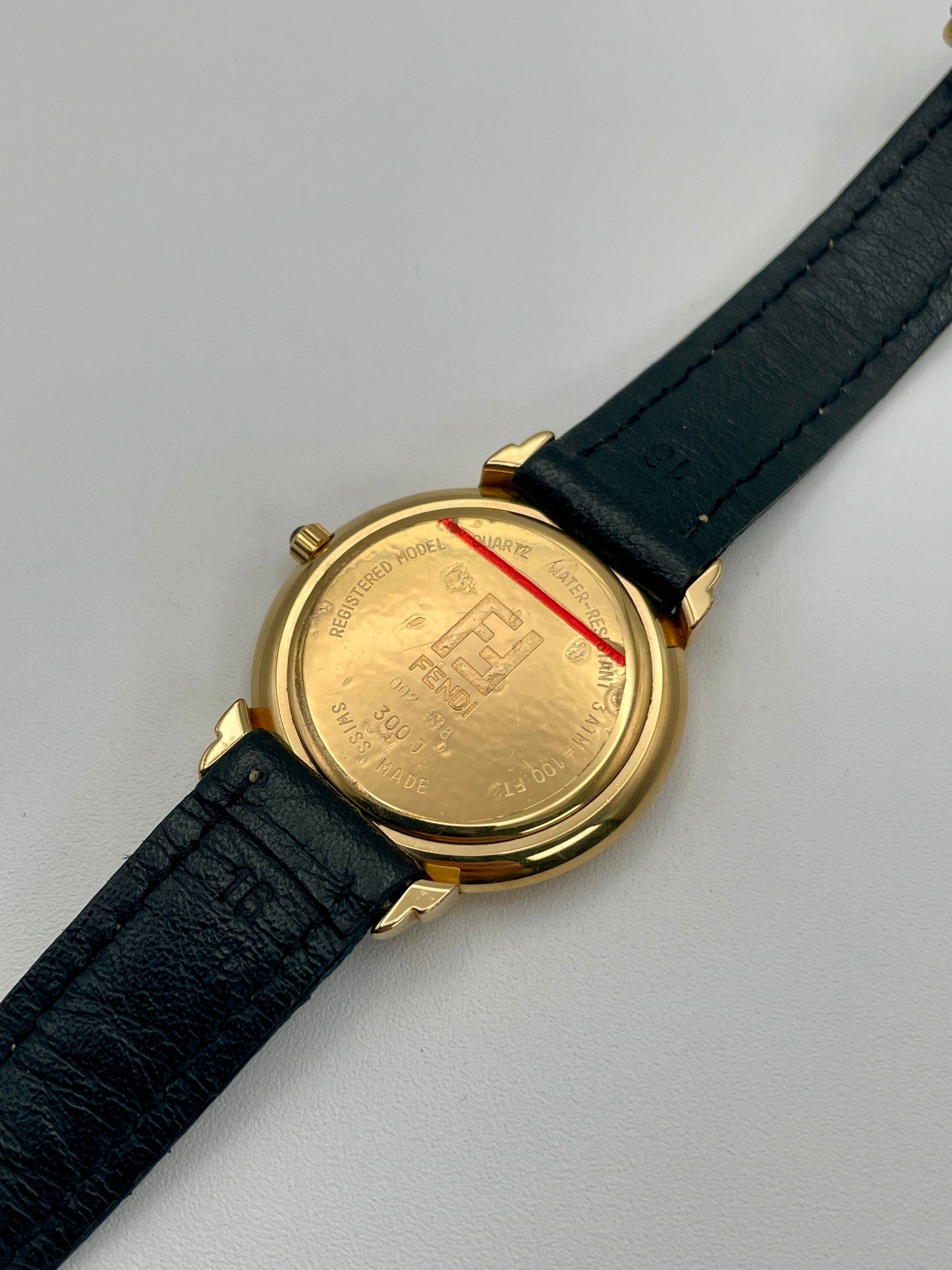 Caseback view of the Fendi 300J revealing engraved brand and model information on the gold surface.