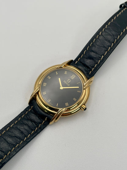 Angled view of the Fendi 300J vintage watch highlighting the round gold case and black stitched leather strap.