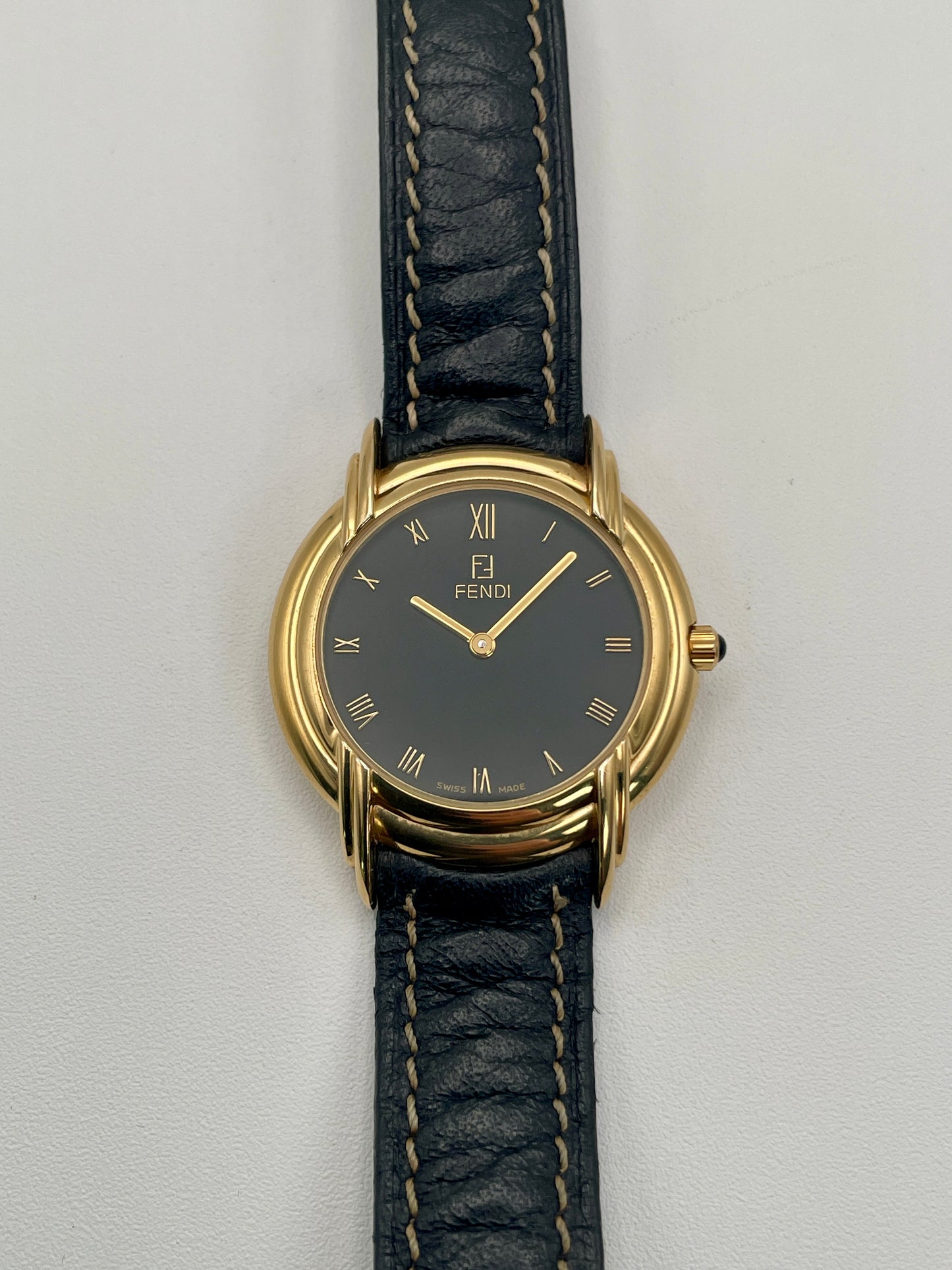 Front view of the Fendi 300J watch showing black dial with gold Roman numerals and triple lug design.