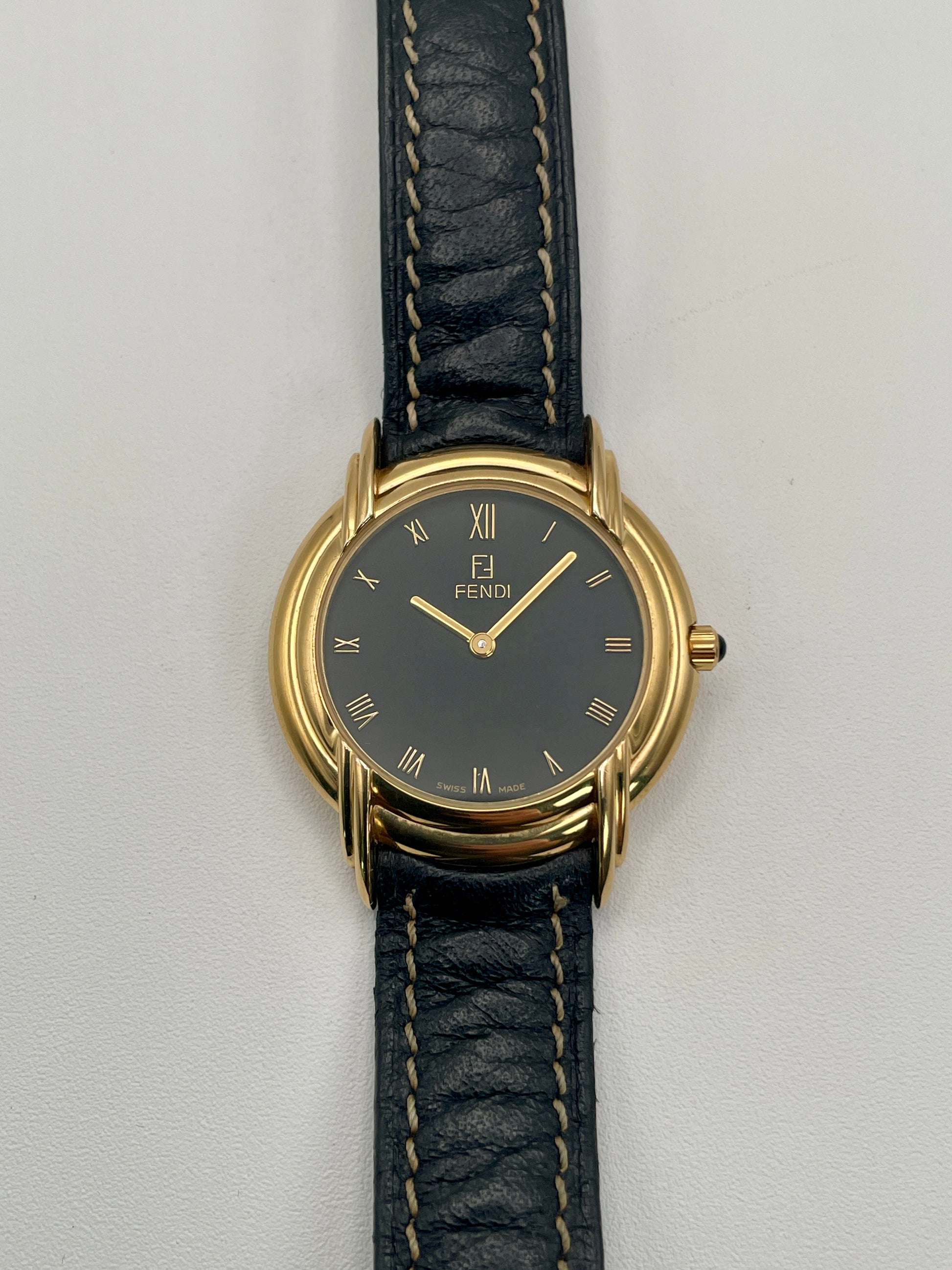 Front view of the Fendi 300J watch showing black dial with gold Roman numerals and triple lug design.