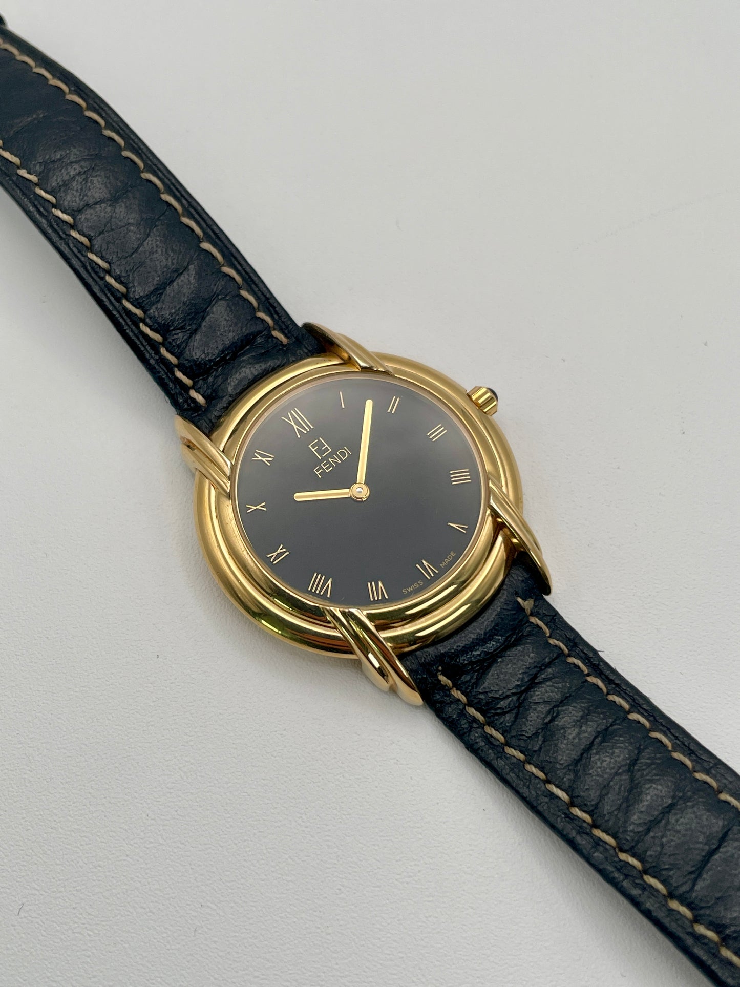 Front view of the Fendi 300J watch showing black dial with gold Roman numerals and triple lug design.