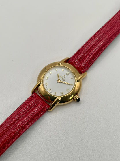 Diagonal angle of the Fendi 410L watch highlighting its round gold-tone case and red lizard strap