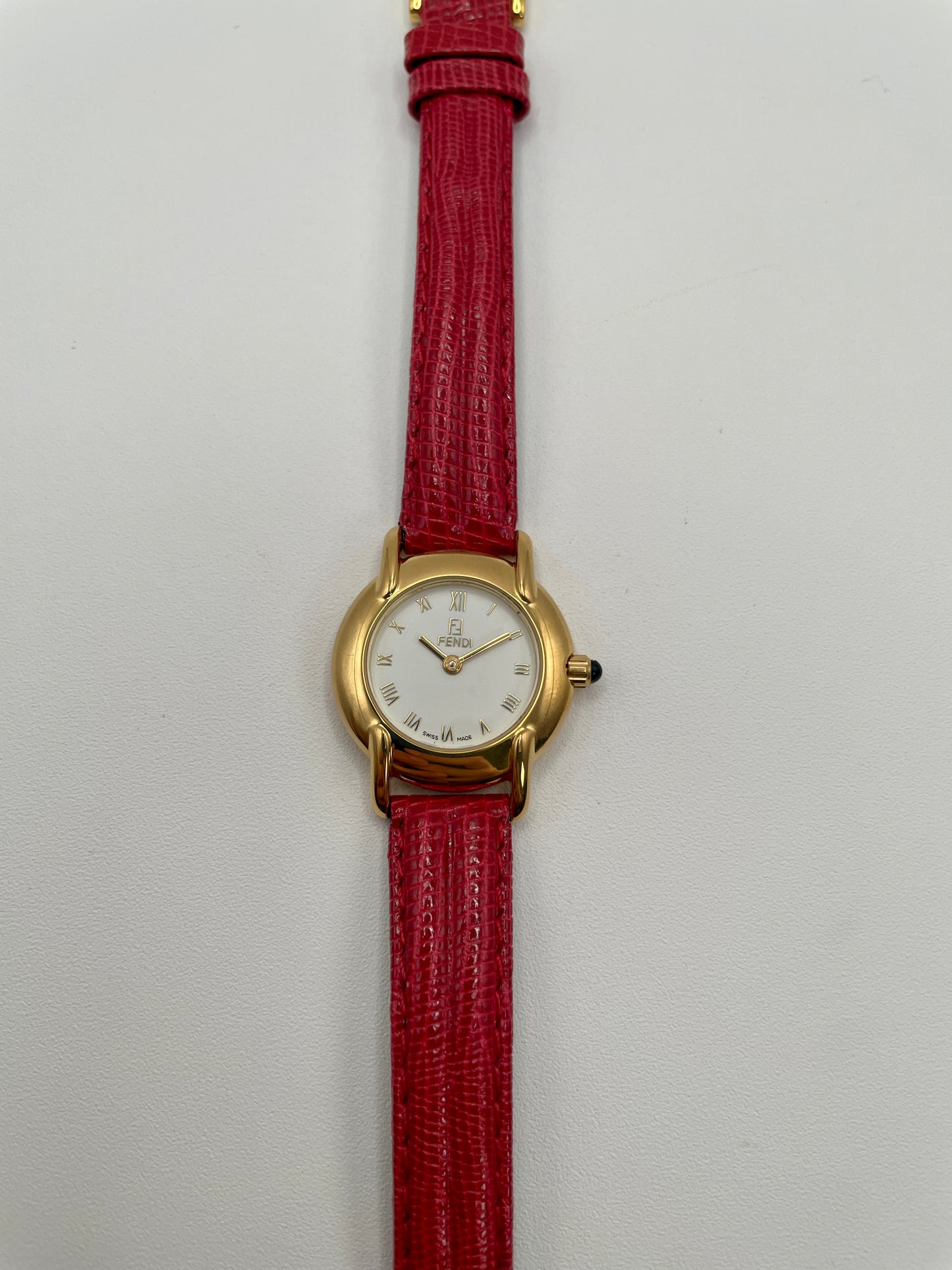 Front view of the Fendi 410L watch showing gold case, white Roman numeral dial, and red leather strap