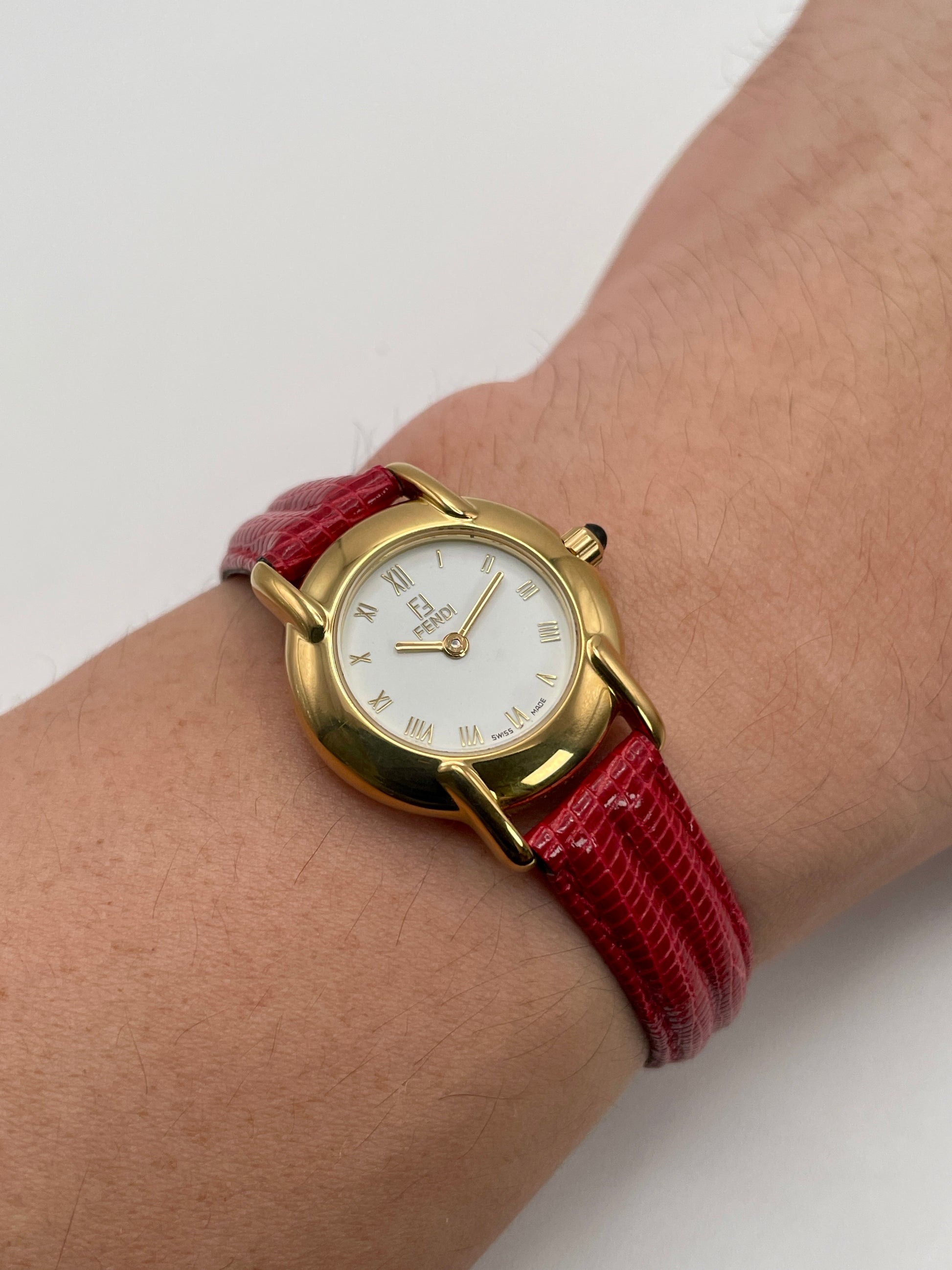 Wrist shot of the Fendi 410L showing how the red strap and gold case sit on the wrist